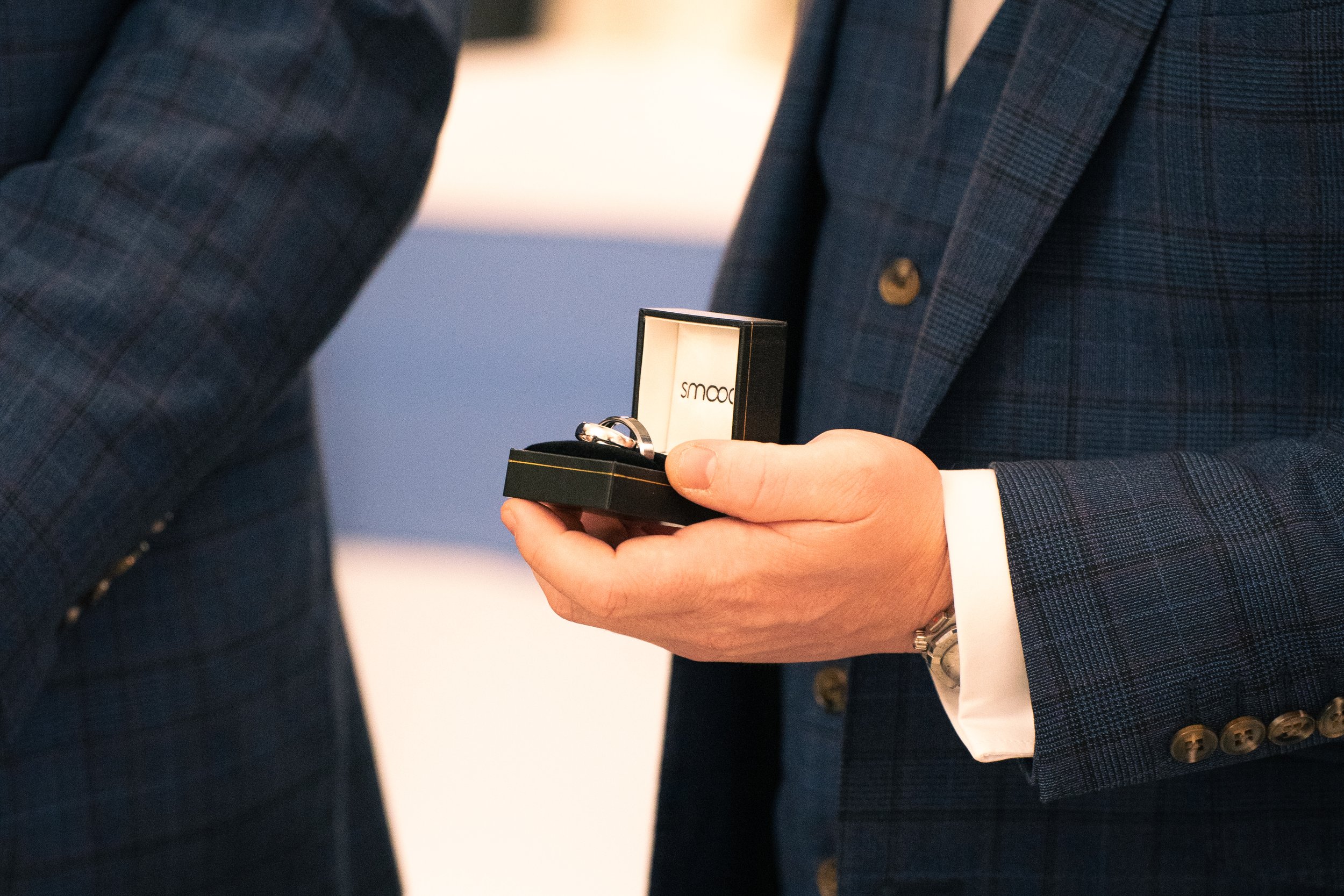 Person in a plaid suit holding a box with a ring inside.