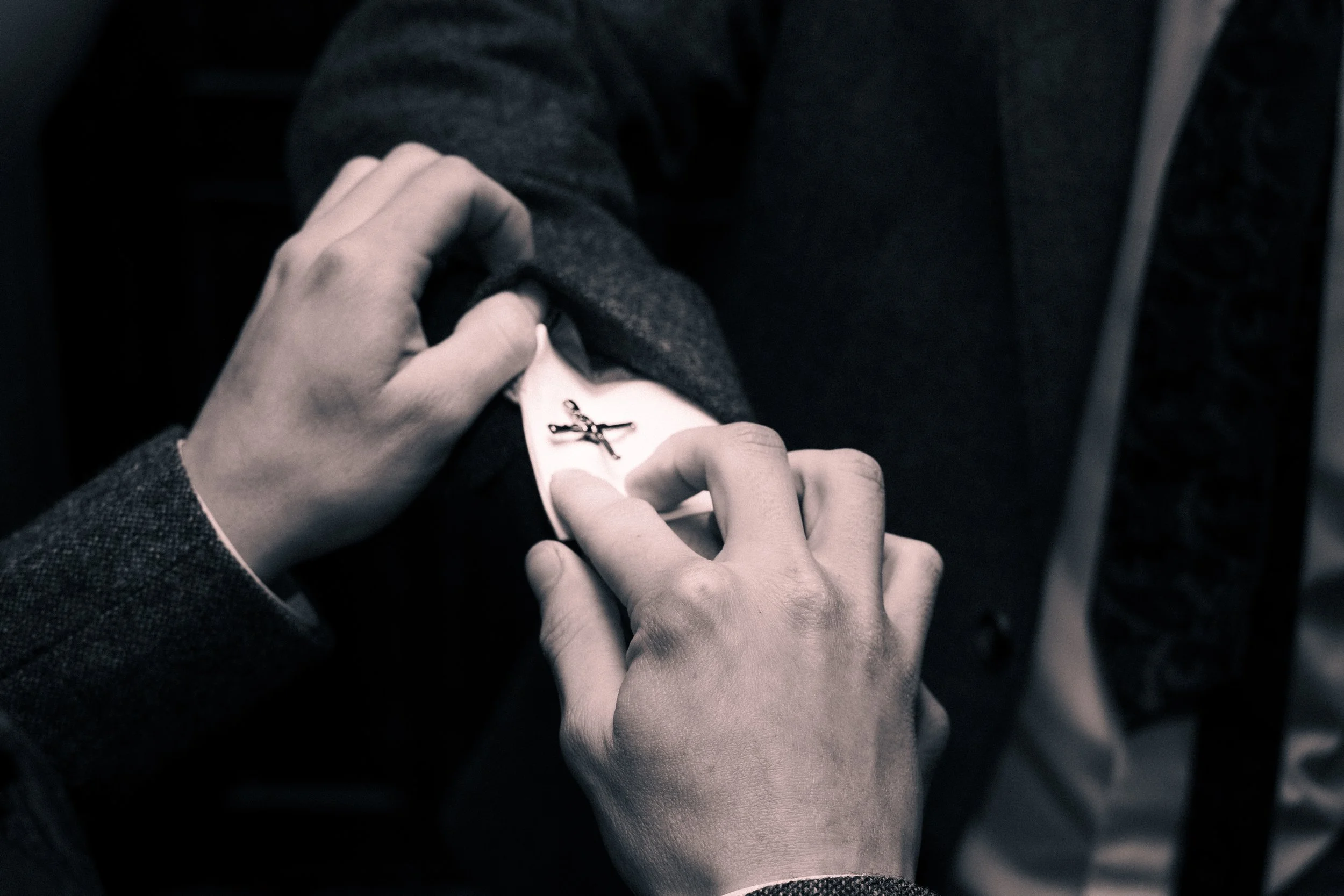 Person placing a pin with a scissors and crossbones symbol on a clothing label.