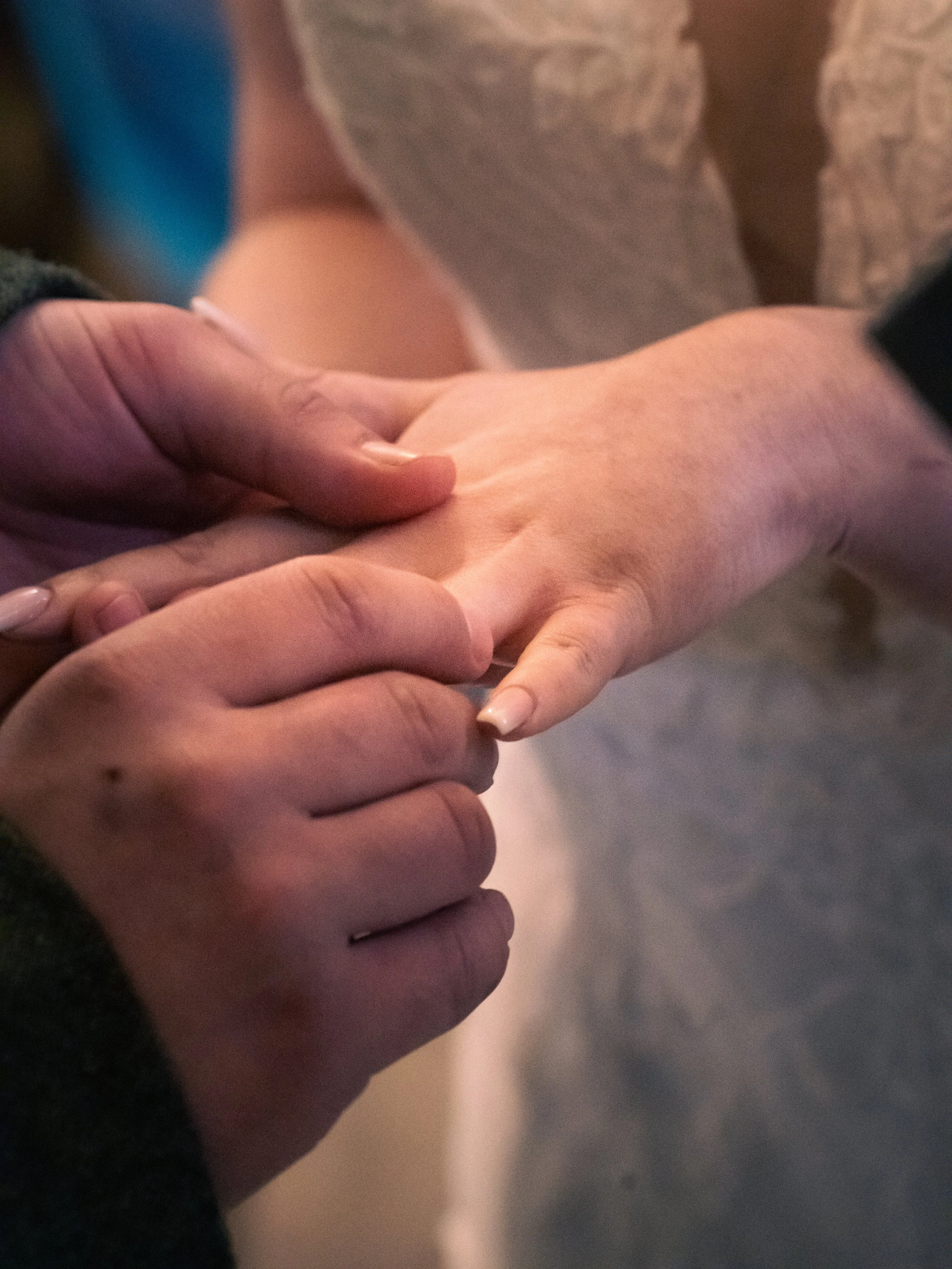 Close-up of two people holding hands, one person's hand gently grasping the other's hand.