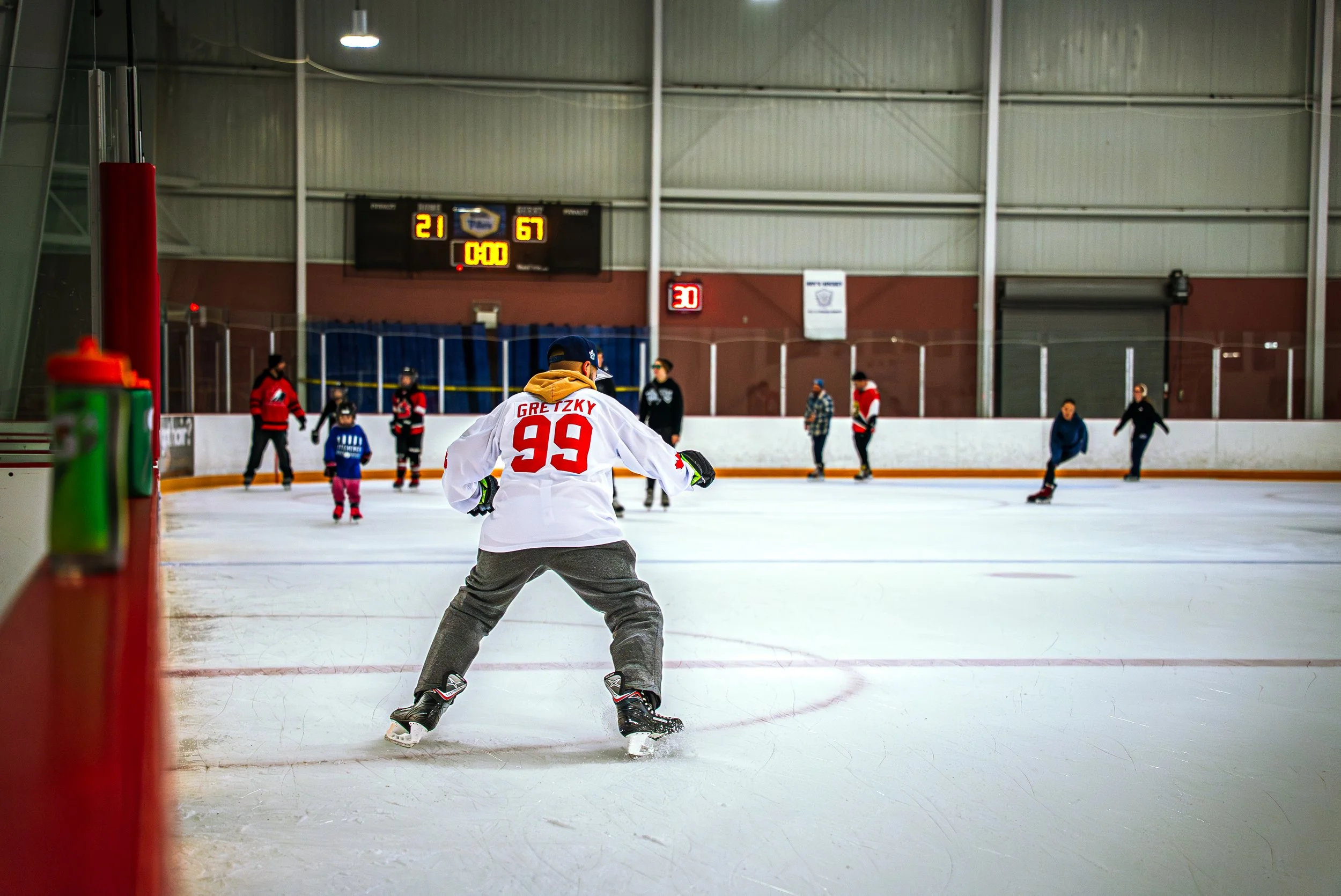 Ice hockey players practicing on an indoor rink, with a prominent player wearing a Gretzky jersey in the foreground.