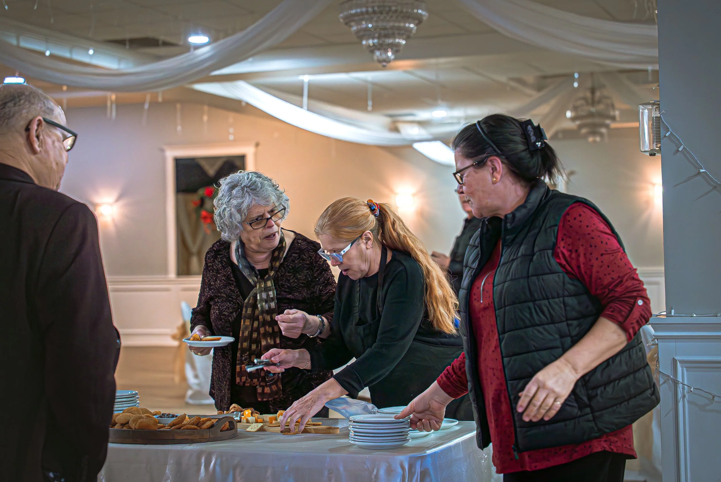 People gathered at a buffet table during a social event, serving themselves food and placing plates.