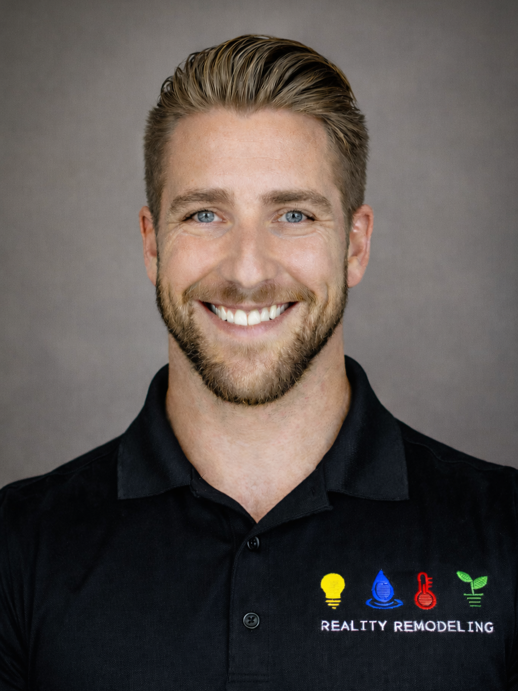 A smiling man wearing a black polo shirt with colorful embroidered icons and the text 'Reality Remodeling'.