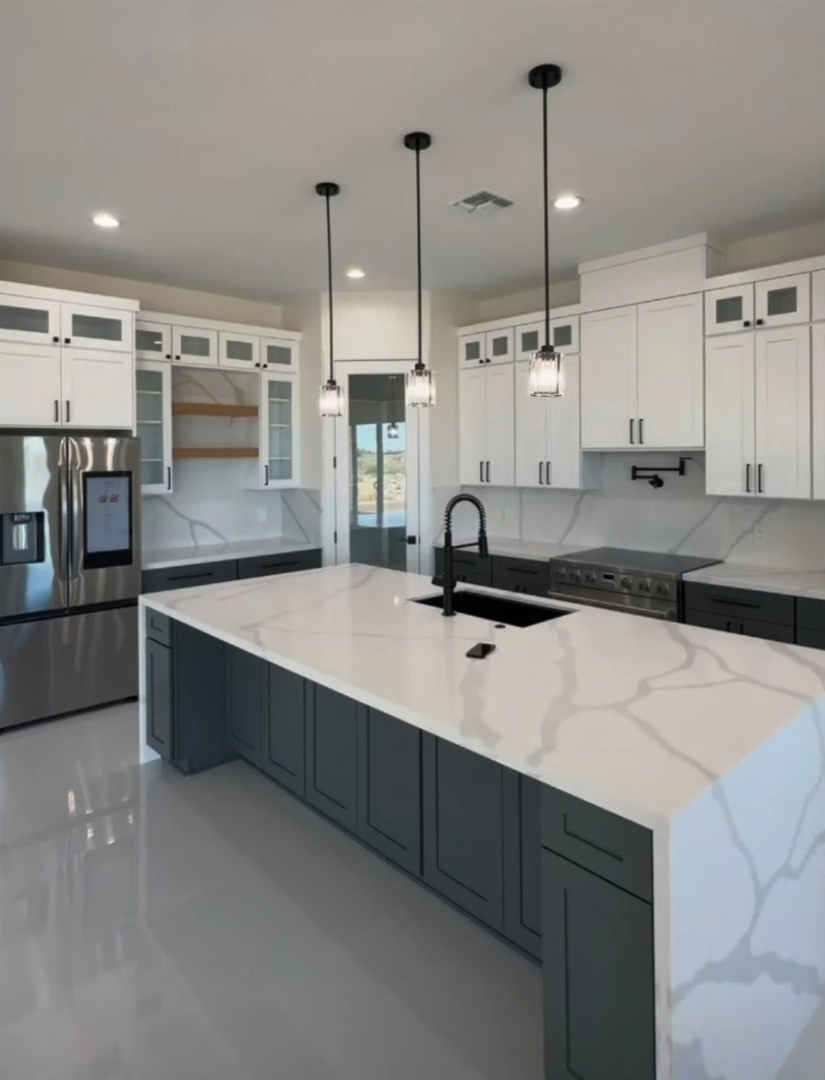 Arizona kitchen remodel featuring white cabinetry, marble countertops, black fixtures, stainless steel appliances, and a large island.