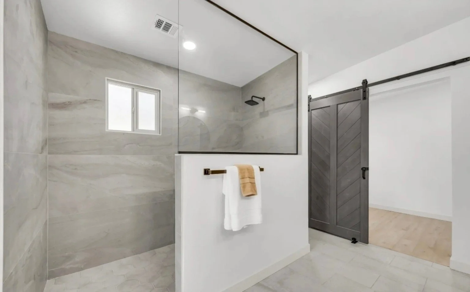 Arizona bathroom remodel featuring a walk-in tiled shower, glass enclosure, black fixtures, and modern finishes