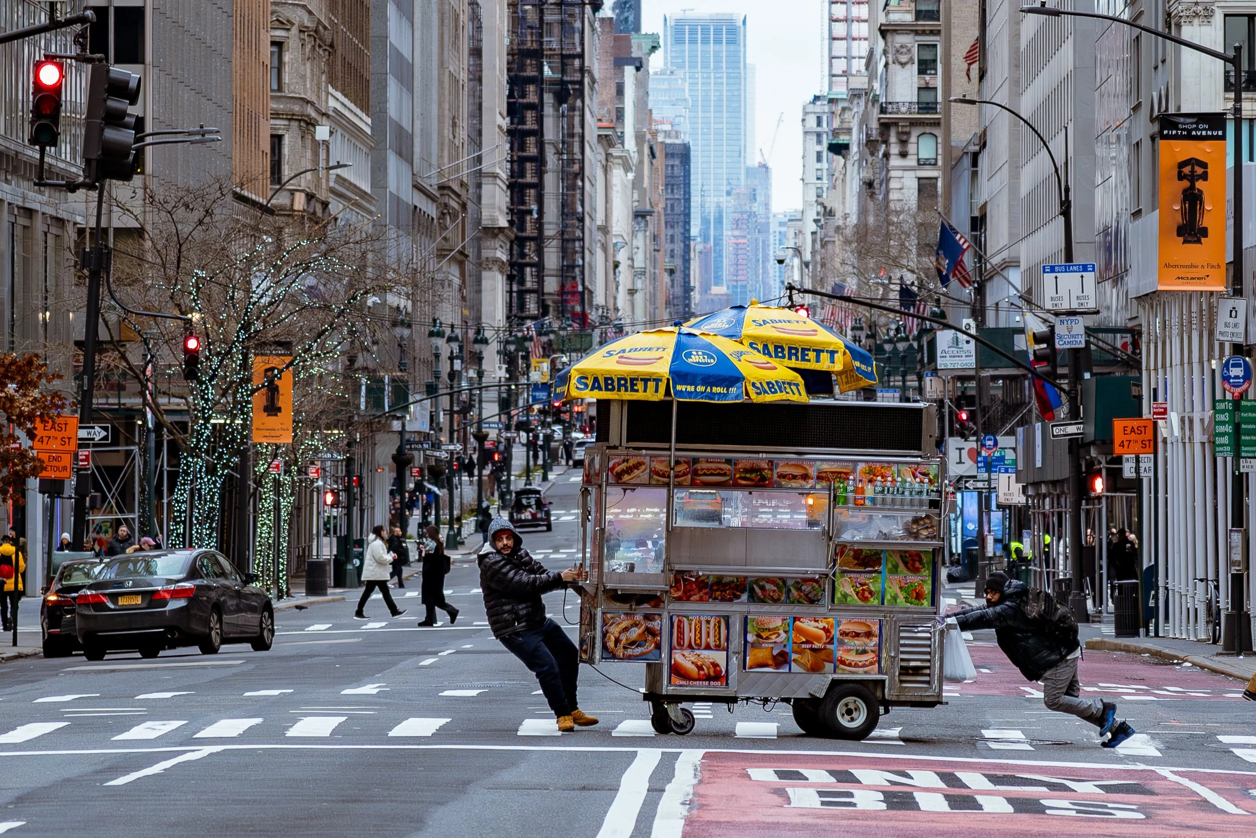 Straatbeeld in een drukke stad met een foodtruck die snacks verkoopt, mensen op straat en hoge gebouwen.