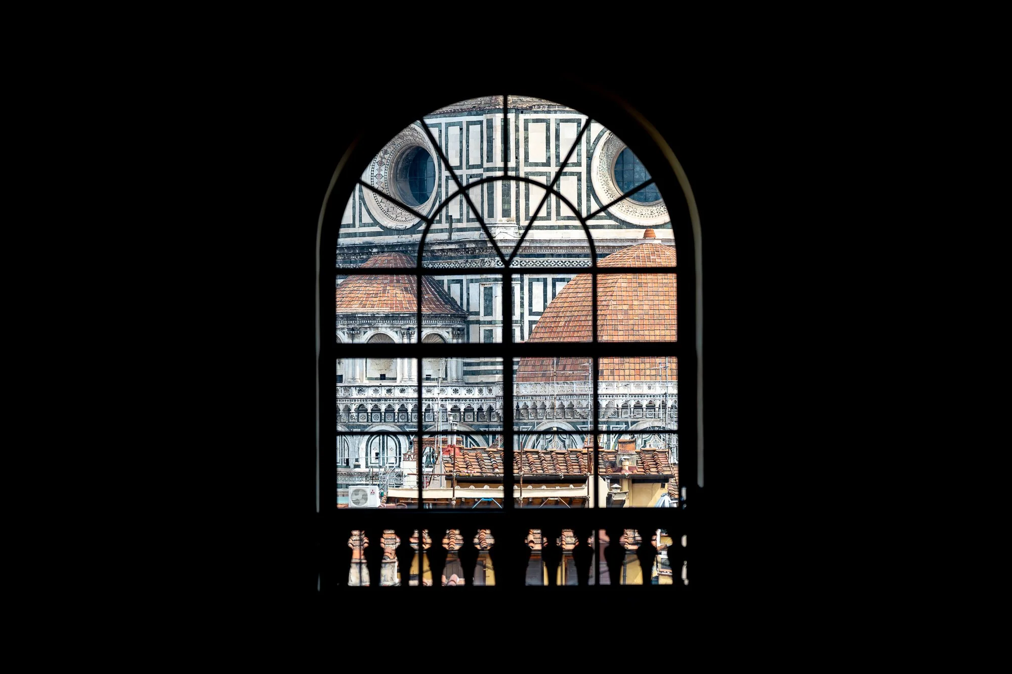 Uitzicht op de Duomo van Florence, Italië, via een raam met metalen rooster en architectonische details, terras met tegelvloer.