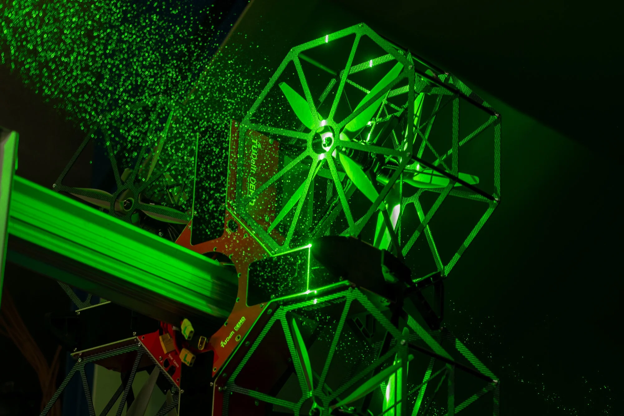 Een complexe laserprojector die groene laserstralen uitstraalt, met geometrische structuren en reflectoren.