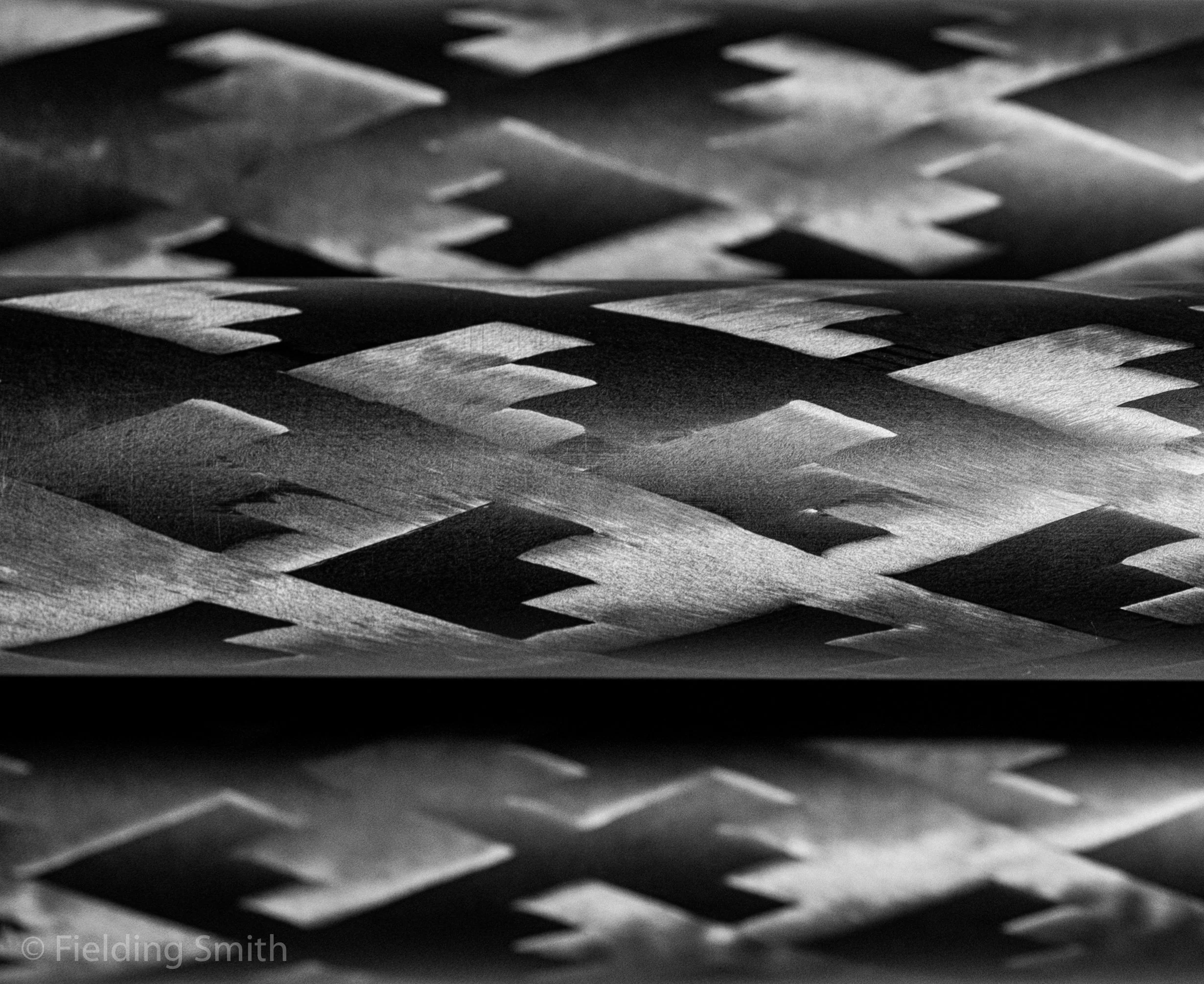 Close-up of woven metal strips creating a textured pattern in black and white.