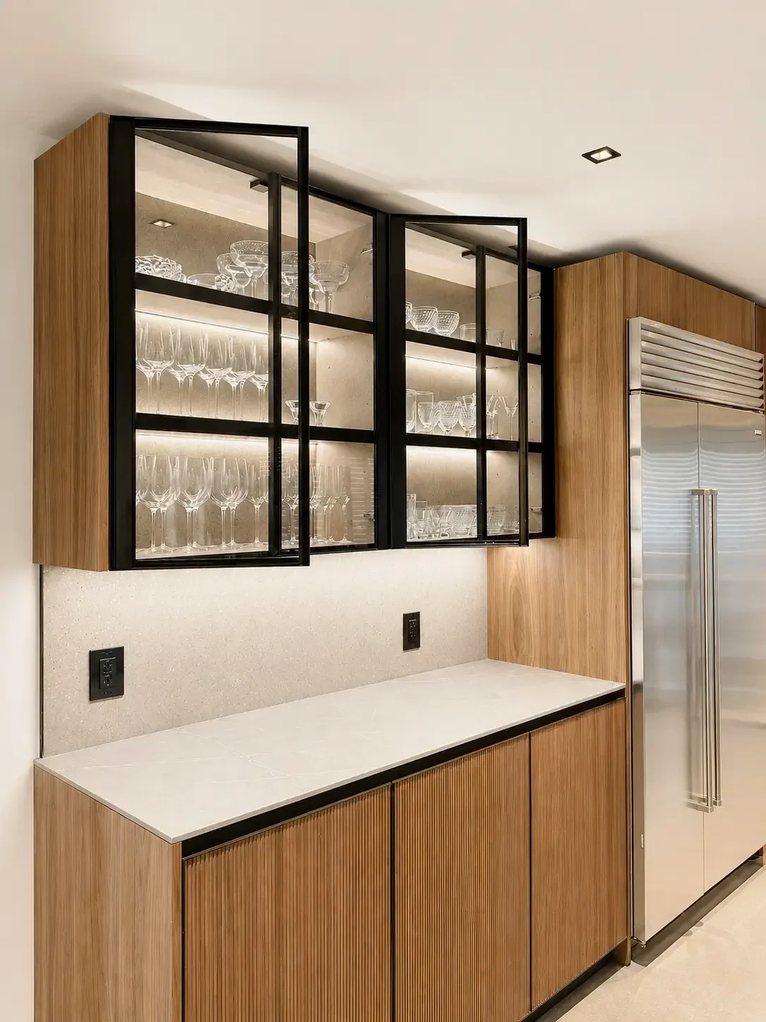 Modern kitchen storage with smoked glass cabinets, ribbed wood doors, and integrated lighting in Franklin Lakes NJ.
