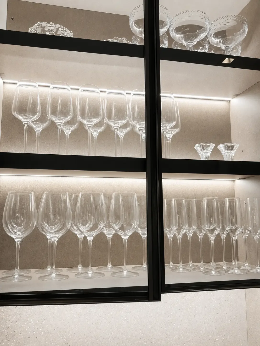 Smoked glass cabinetry with metal profile and duplex shelf lighting in this modern kitchen in Franklin Lakes NJ.