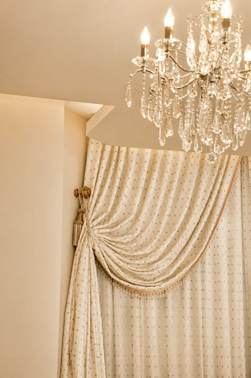 Crystal chandelier and tailored drapery detail in a semi-classical villa interior designed in Sharjah.