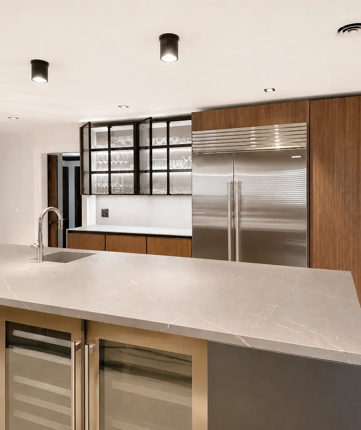Luxury kitchen design with marble island, stainless steel appliances, and glass display cabinets in Franklin Lakes NJ.