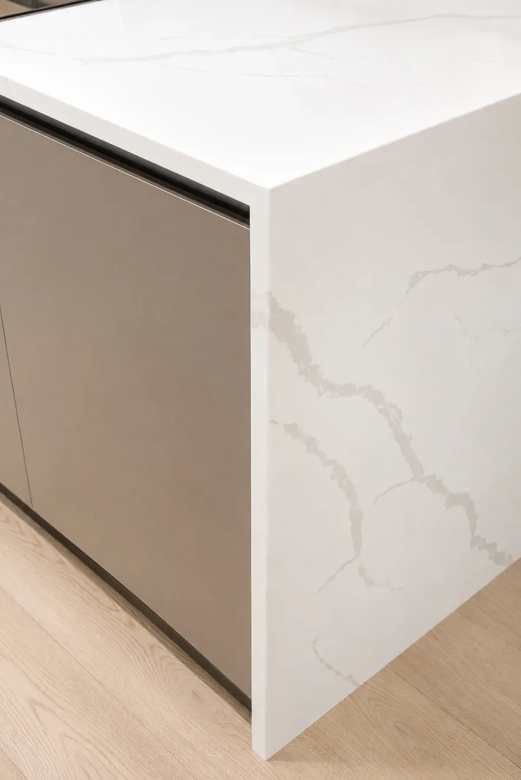 Quartz waterfall island detail with metallic finish cabinetry in a transitional kitchen project in Woodland Park New Jersey.