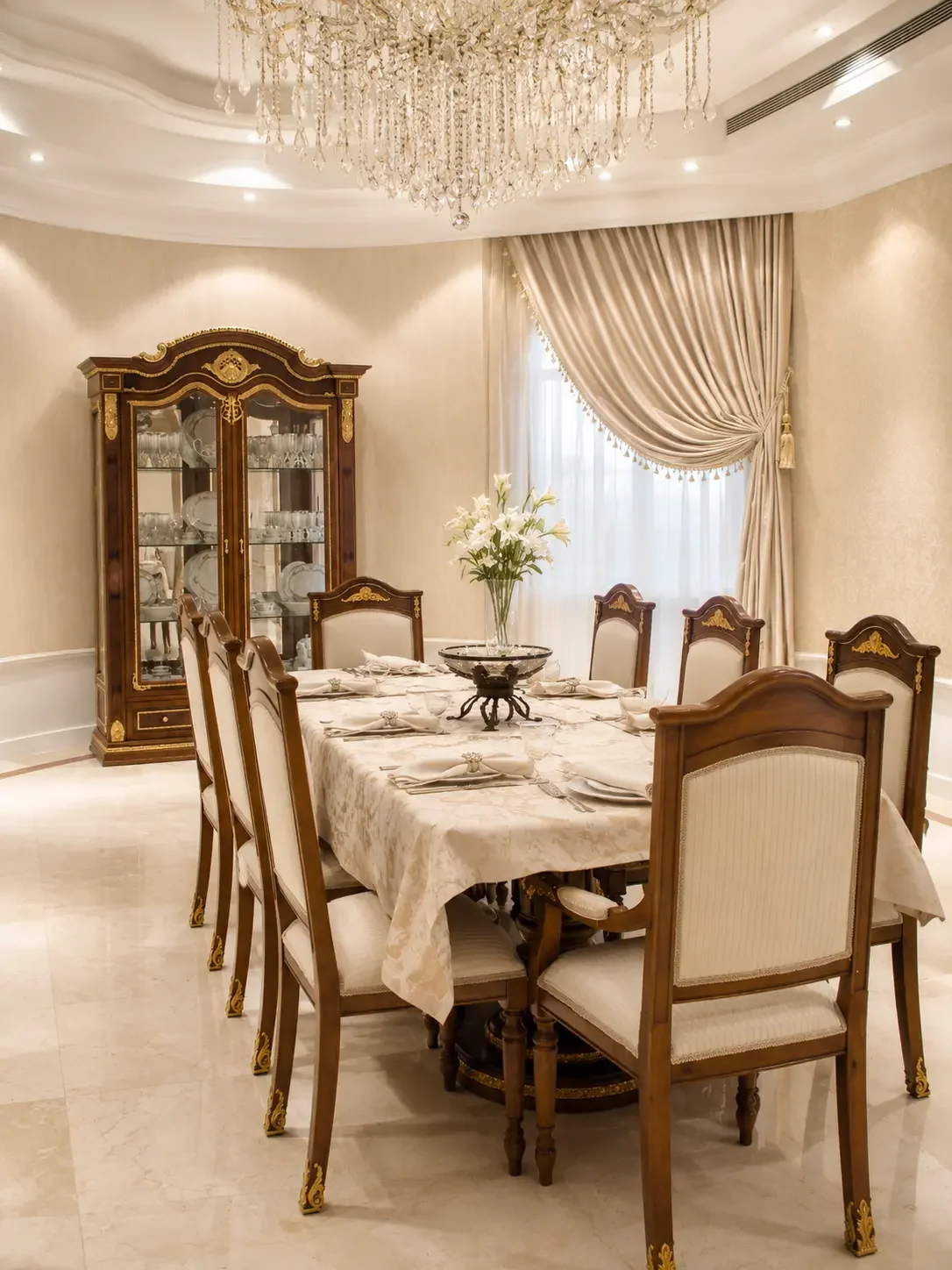 Semi-classical dining room in a Sharjah villa featuring custom wood dining furniture, crystal chandelier, and tailored drapery.