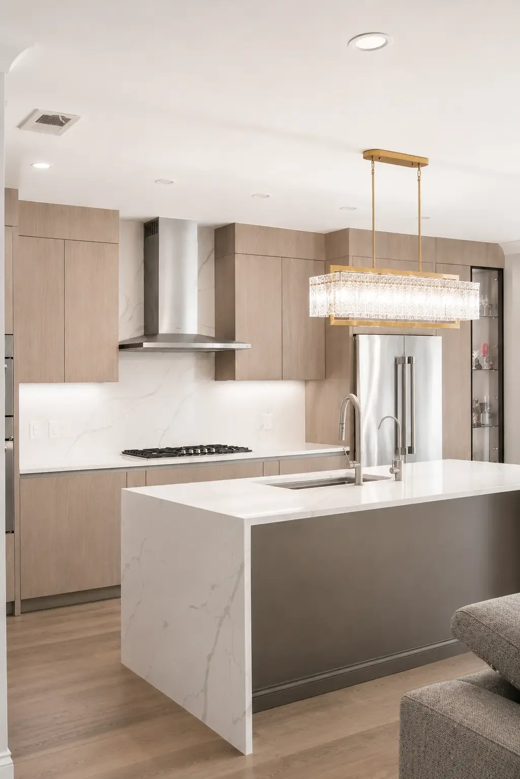Transitional kitchen in Woodland Park NJ with light oak cabinetry, waterfall island, and quartz backsplash.