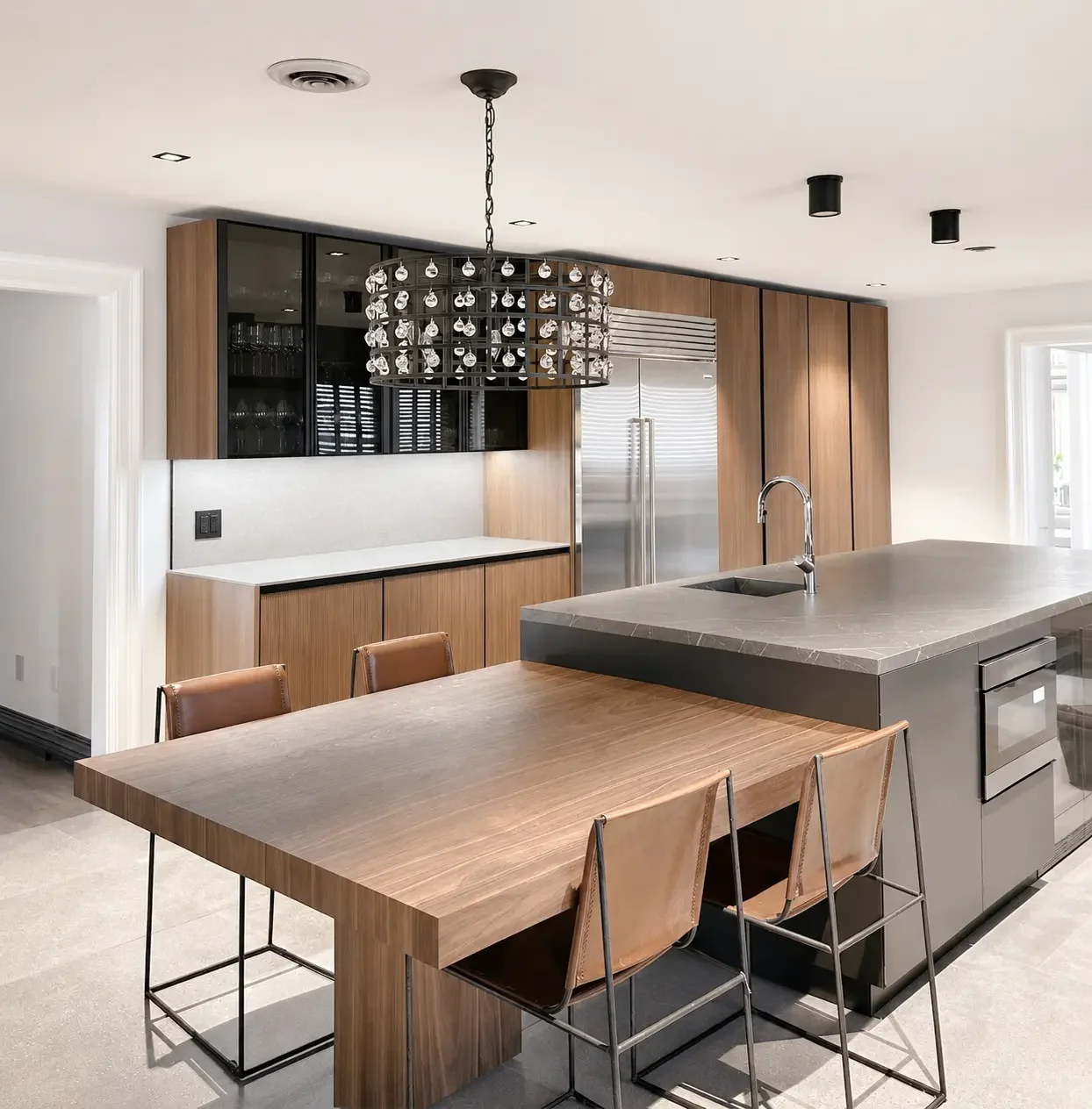 Modern kitchen in Franklin Lakes NJ with wood cabinetry, island seating, pendant lighting, and integrated dining table