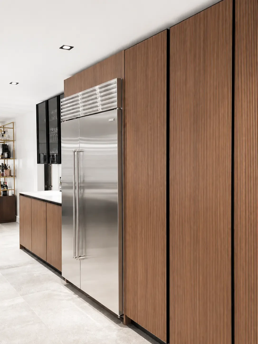 Ribbed wood refrigerator wall and tall pantry with integrated vertical handles in a modern Italian kitchen in Franklin Lakes NJ.