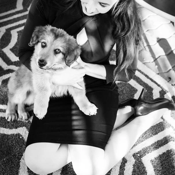 A woman sitting on a rug holding a puppy, photo in black and white.