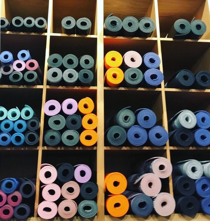 Colorful yoga or exercise mats rolled up and organized in a cubby shelf.