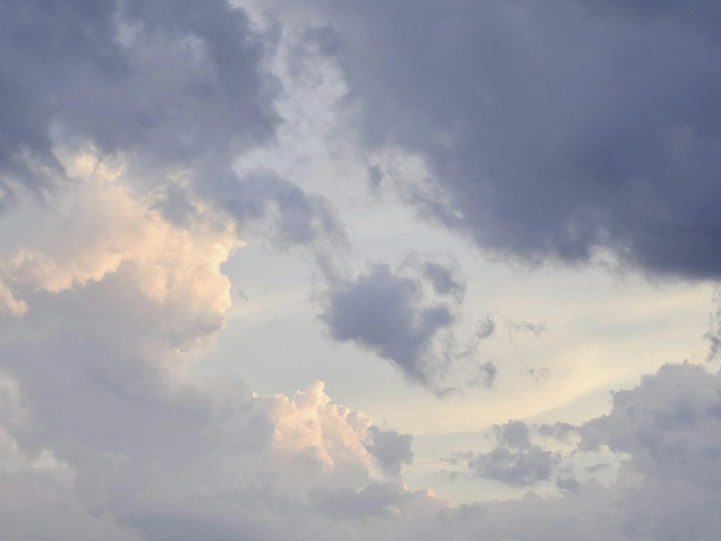 Gray sky with clouds, some showing pink, yellow hues indicating sunset or sunrise.