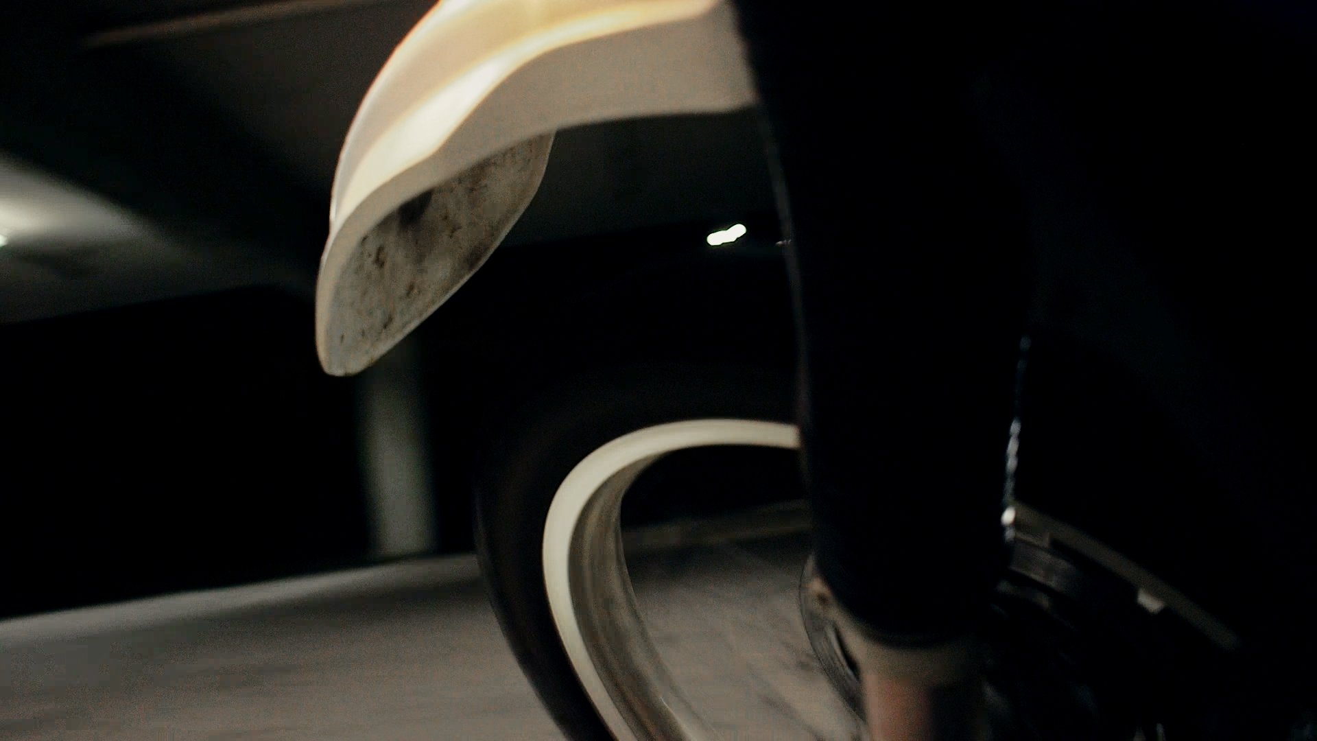 Close-up of a motorcycle tire in motion, driving on a road, detailed tread in focus, dynamic motion blur, cinematic lighting, high-contrast, realistic style.