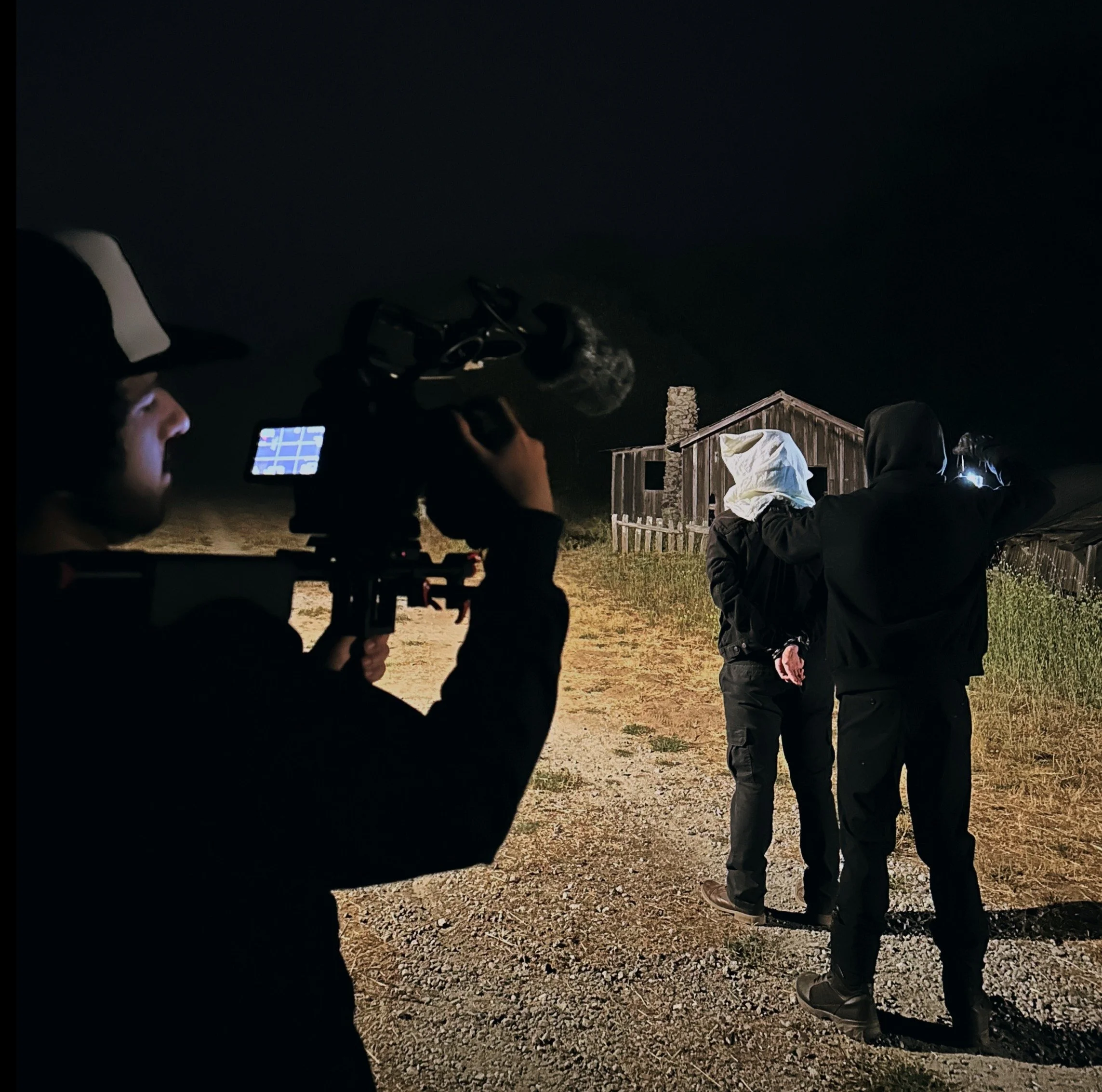 Behind-the-scenes of a director holding a camera, preparing to film a tense scene in an abandoned building where one actor is holding another hostage, cinematic lighting, gritty film set atmosphere, realistic style.