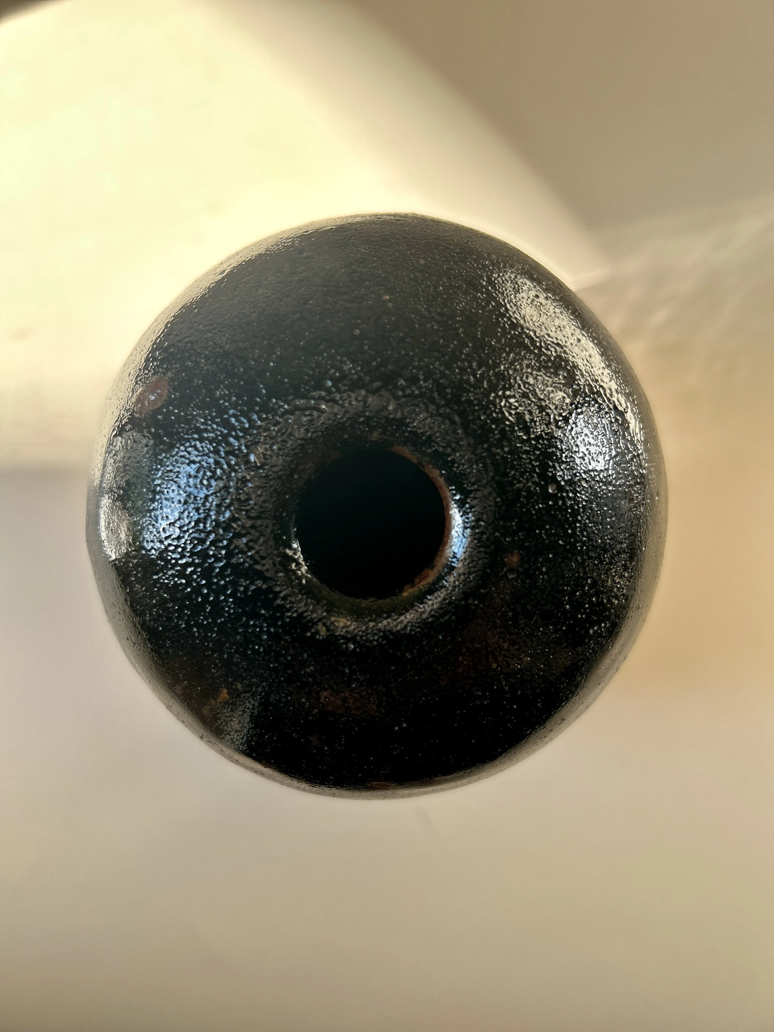 Signed 1989 studio pottery vessel with glossy black tenmoku-style glaze, exposed brown stoneware clay and small bud vase opening.