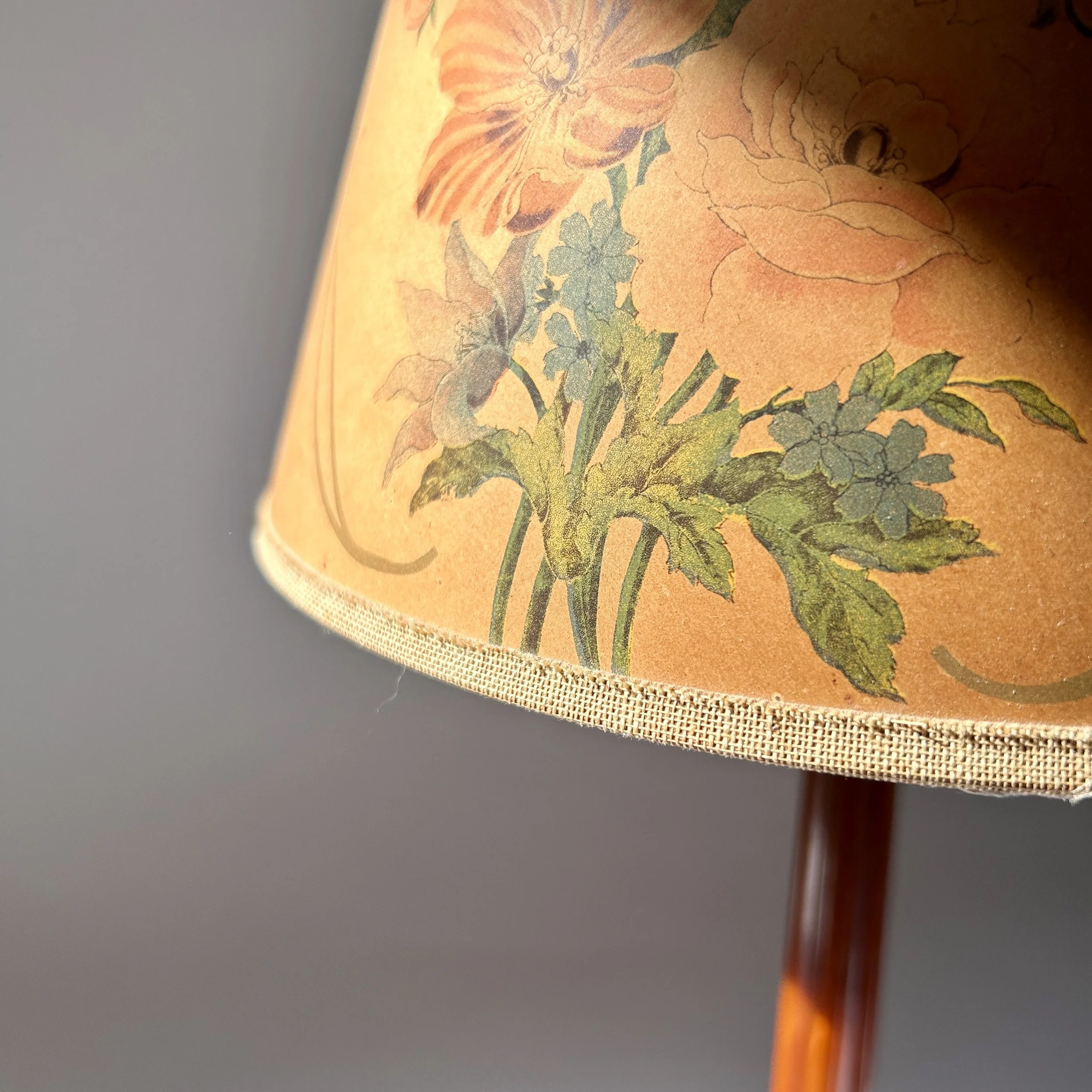 Vintage amber Bakelite table lamp with stepped geometric base, slender column, and warm brown floral lampshade.