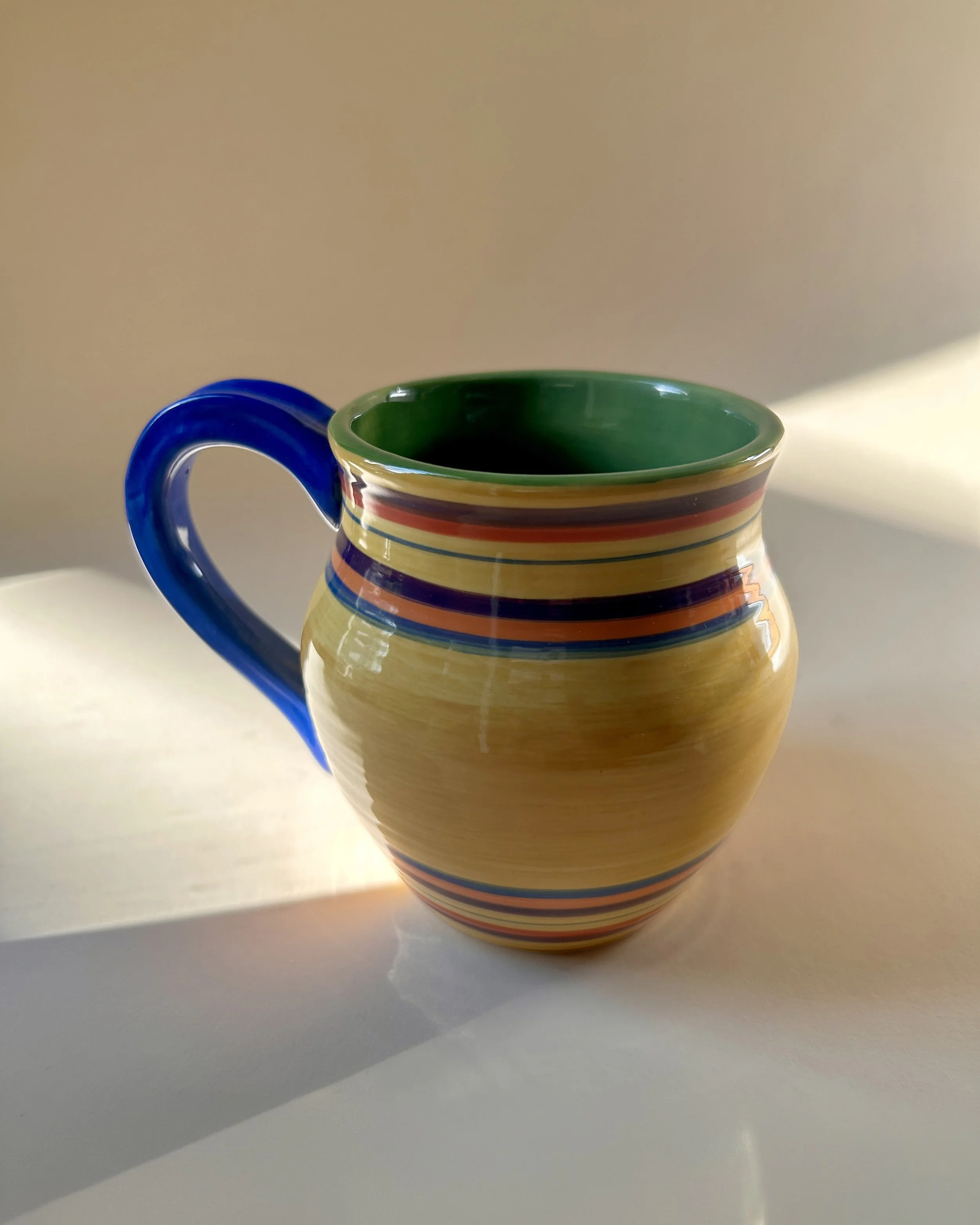Set of three colorful Pacific Rim Santa Fe stoneware mugs with hand-painted multicolor stripes and contrasting handles and interiors.