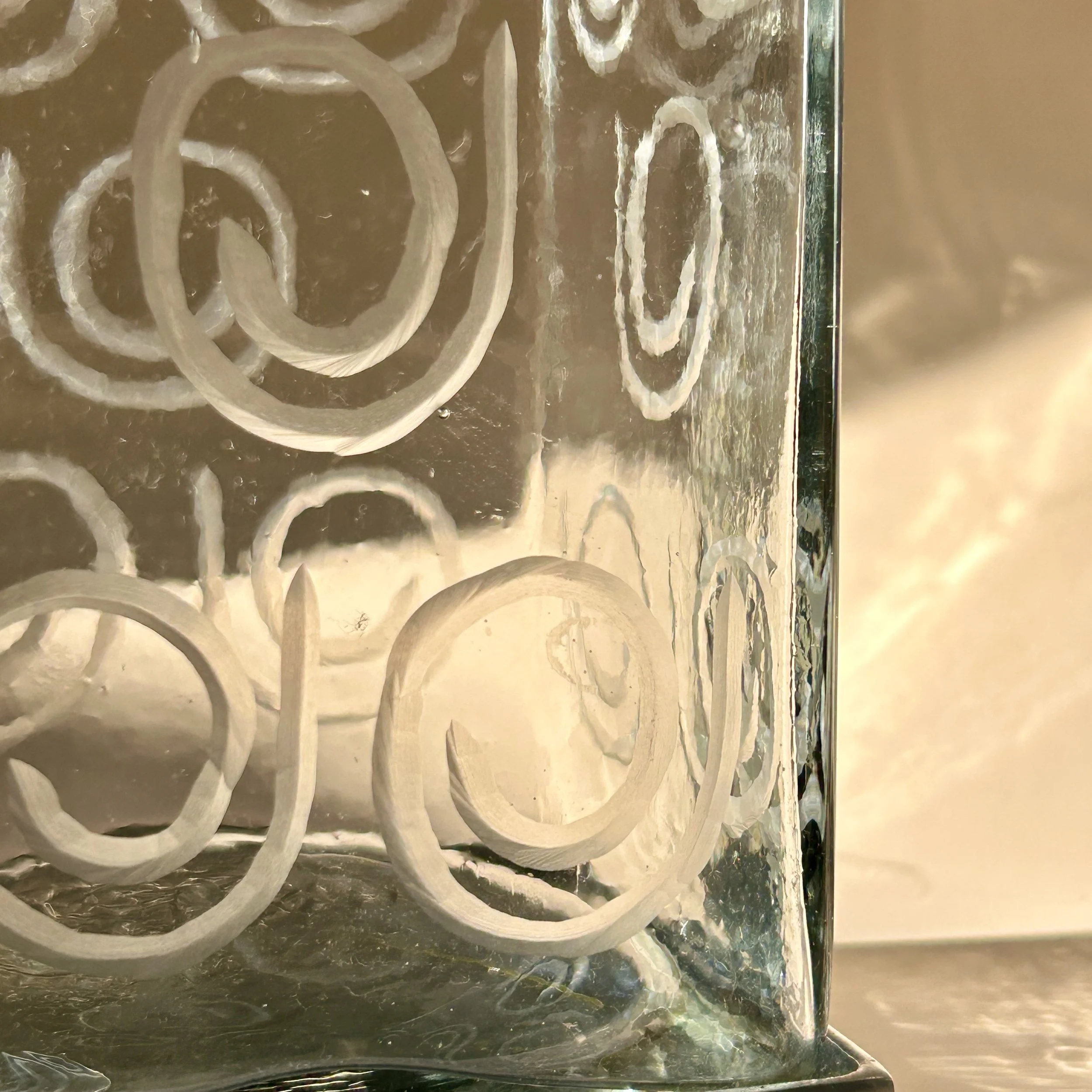 Contemporary square clear glass canisters with etched spiral patterns, silver-tone metal bases, and peaked metal lids in two different heights.