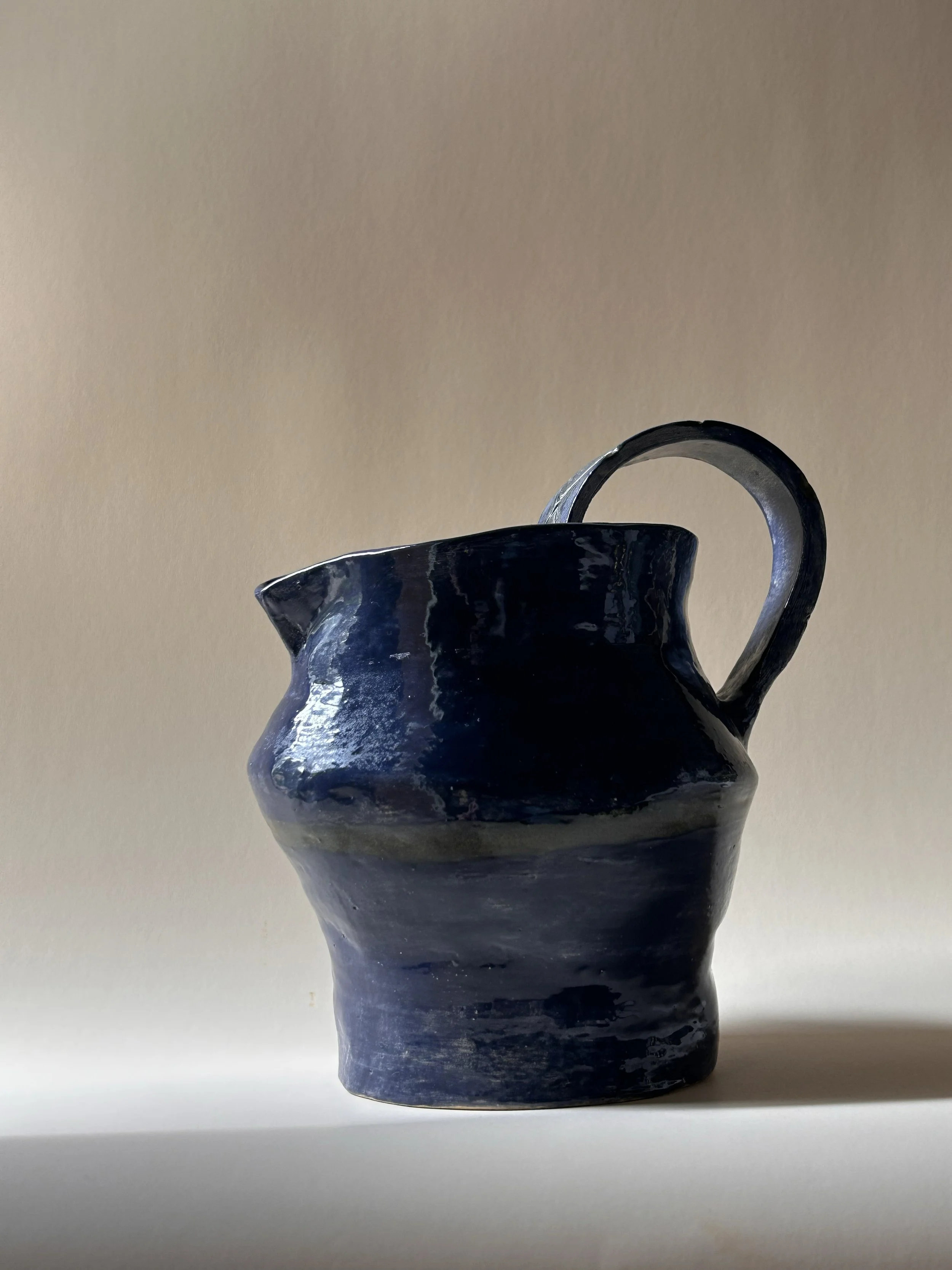 hand built dark blue studio pottery pitcher with sculptural handle
