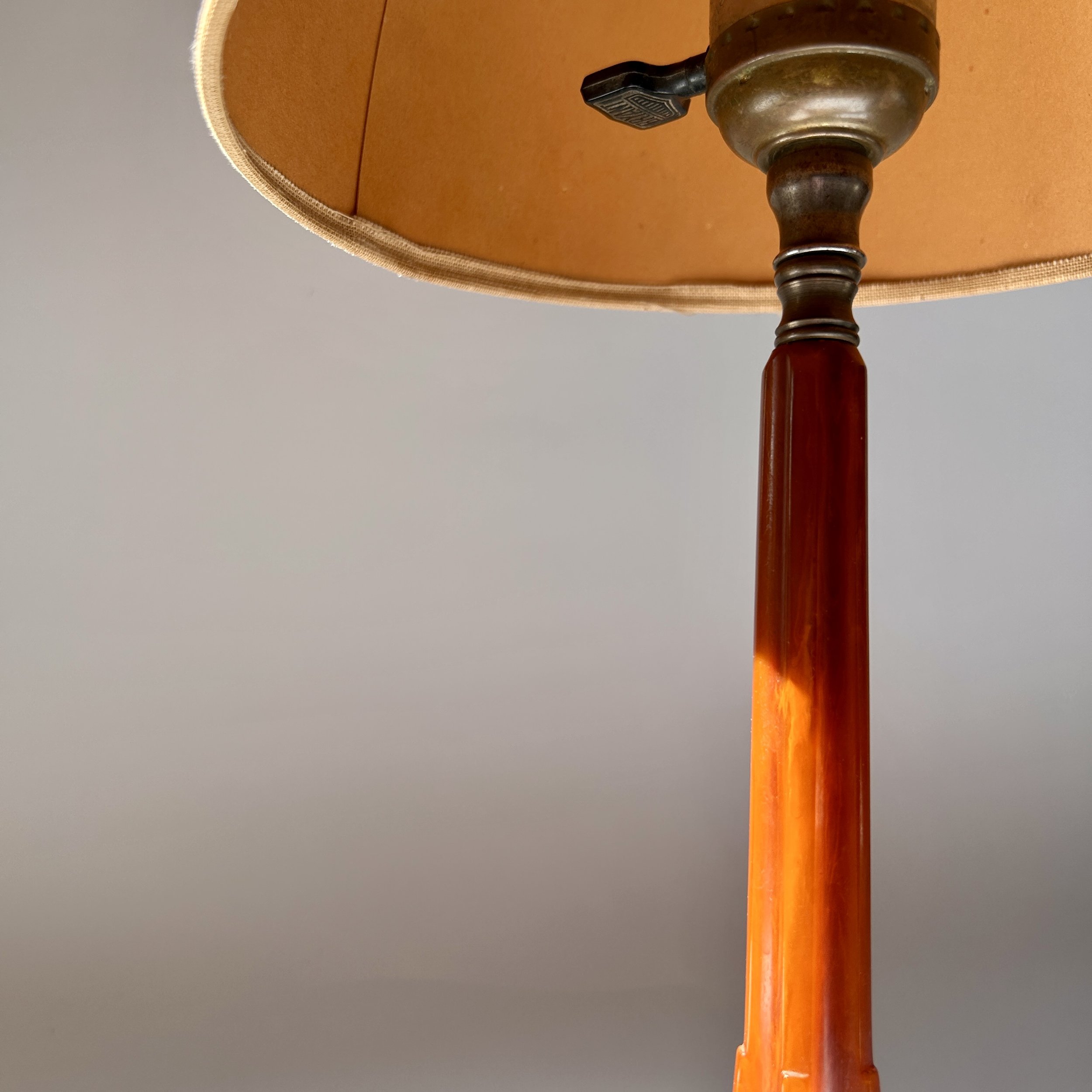 Vintage amber Bakelite table lamp with stepped geometric base, slender column, and warm brown floral lampshade.