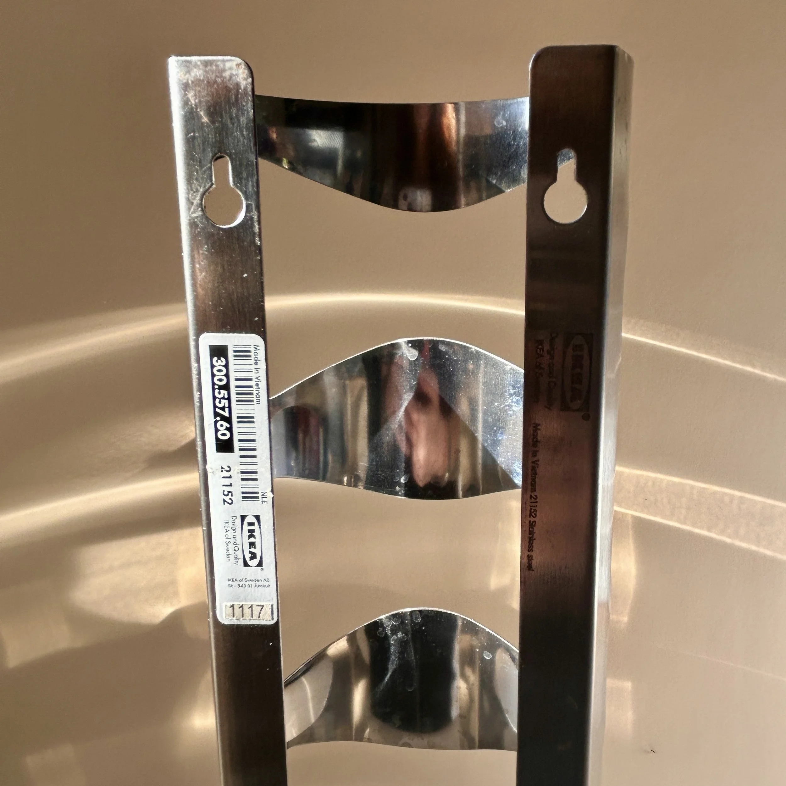 Discontinued IKEA VURM stainless steel wall-mounted wine rack by Karl Malmvall with four curved bottle holders.