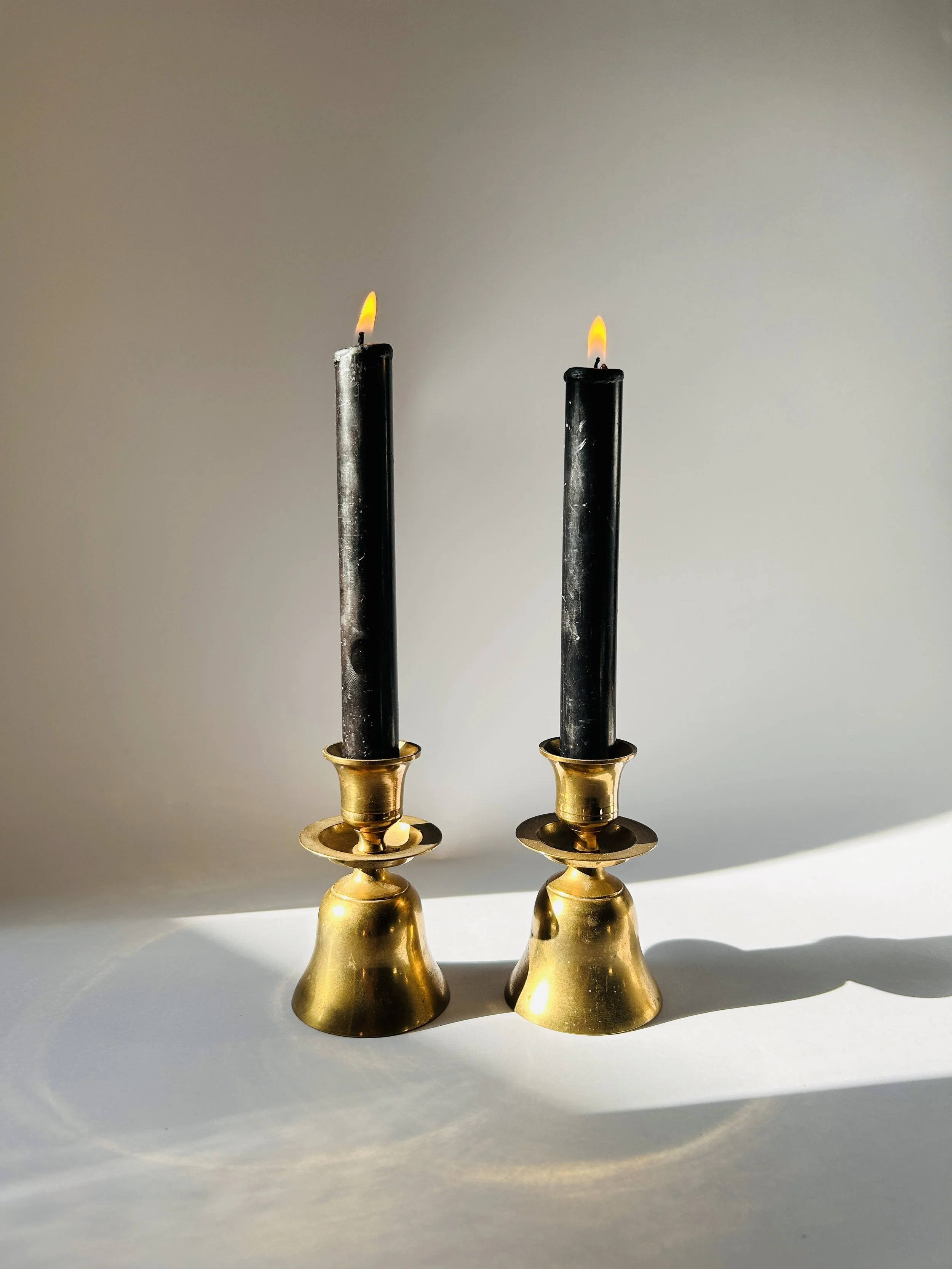 Vintage brass bell shaped candlesticks with black taper candles, mid century candle holders pair