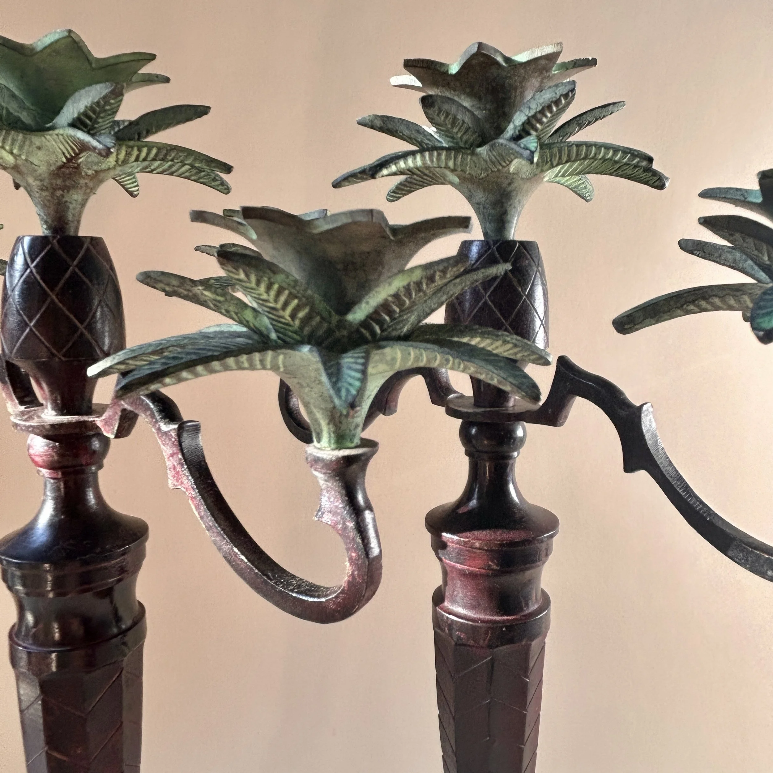 Pair of tall vintage three light candelabras with dark ornate bases, sweeping arms and sculptural green patinated palm leaf candle cups.