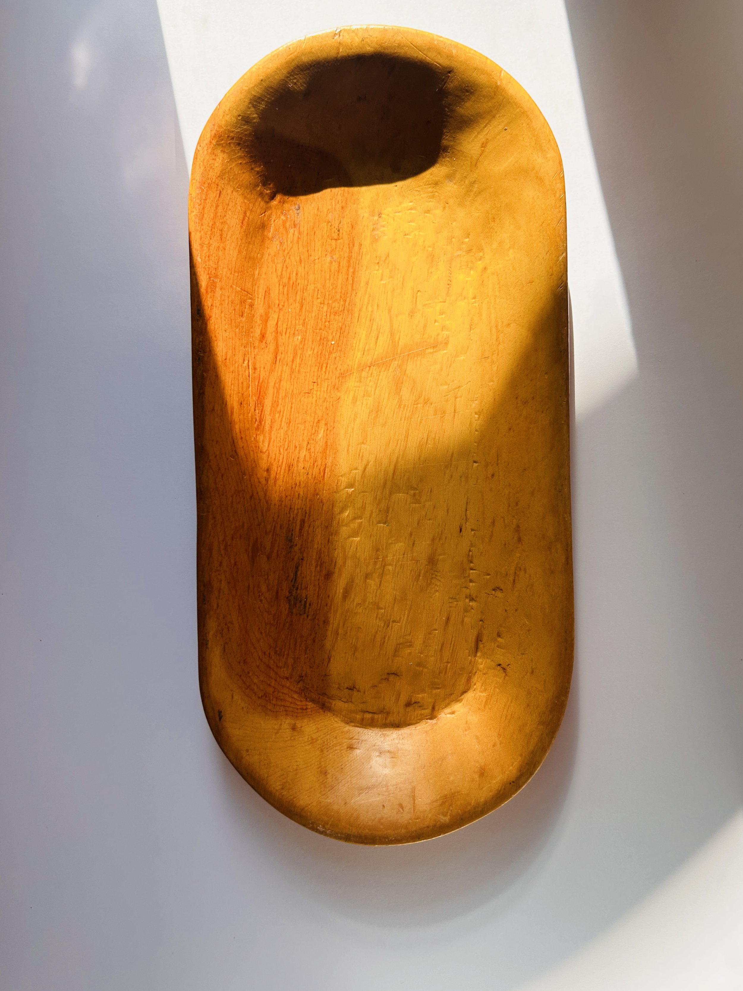Primitive hand-carved wooden tray with organic shape and warm patina, rustic serving board