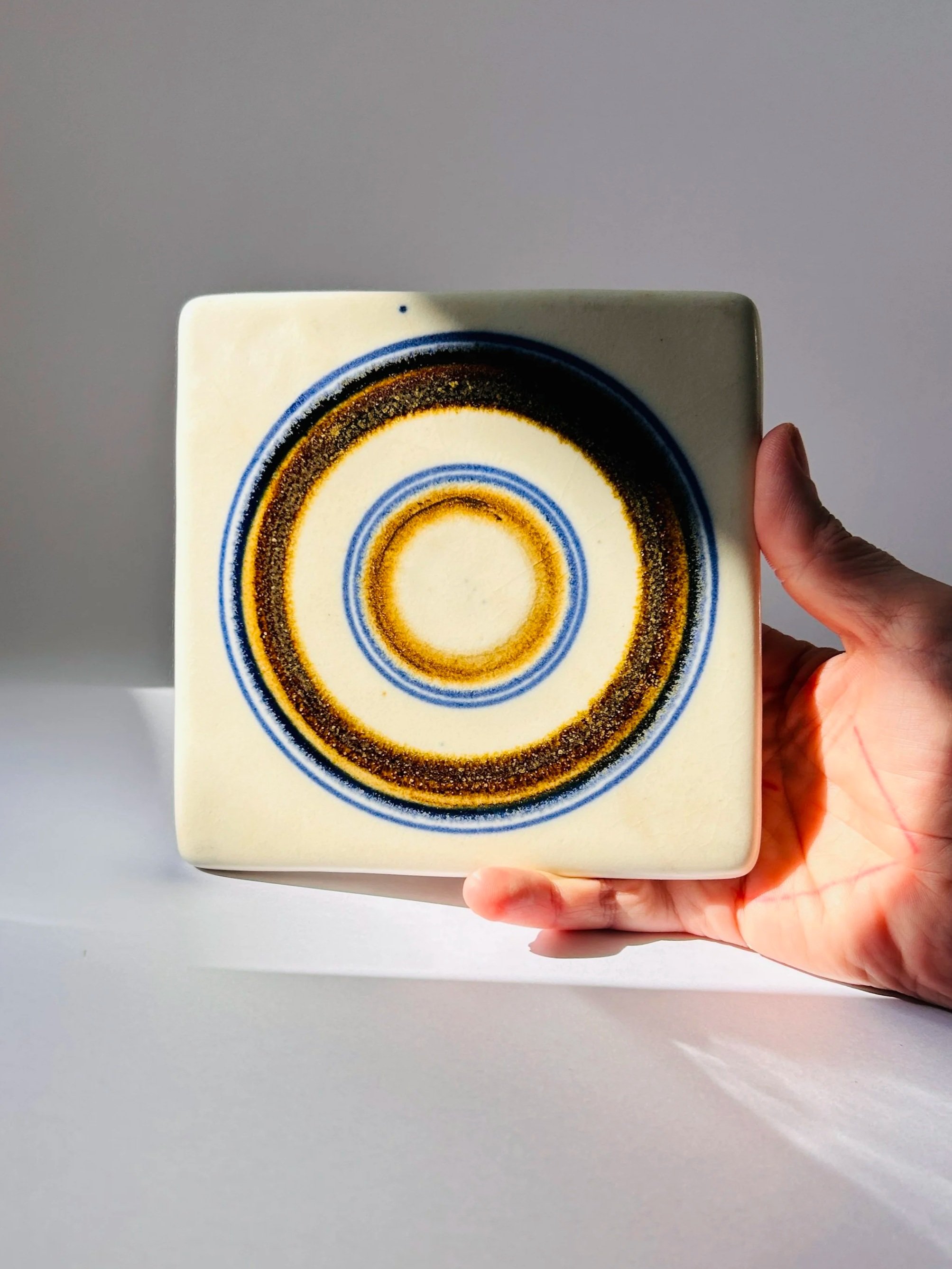 Vintage Arabia Finland Wellamo ceramic trivet with concentric circle design in blue and ochre tones