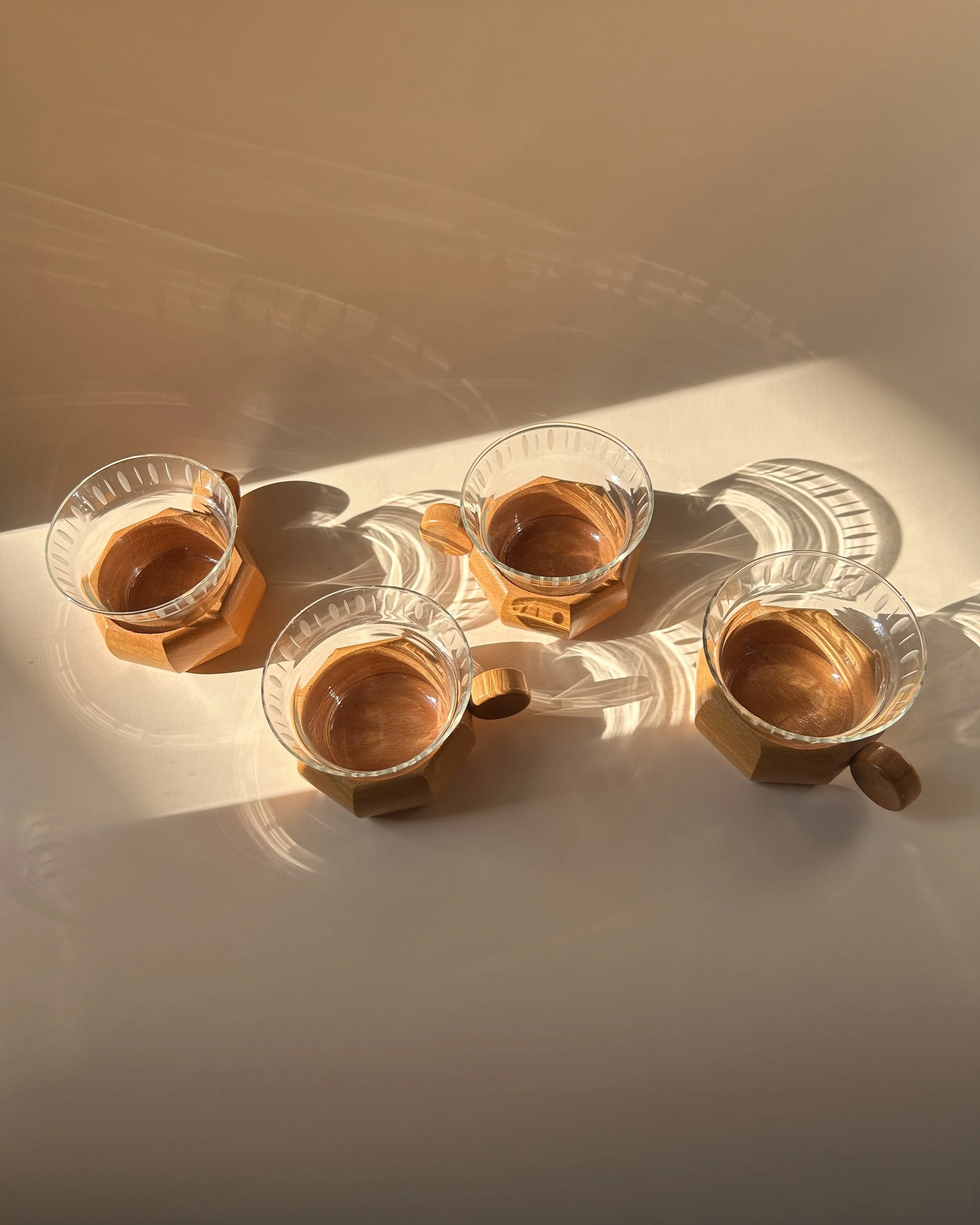 Set of four vintage German clear glass tea cups with frosted oval decoration, faceted wooden holders and round wood handles.