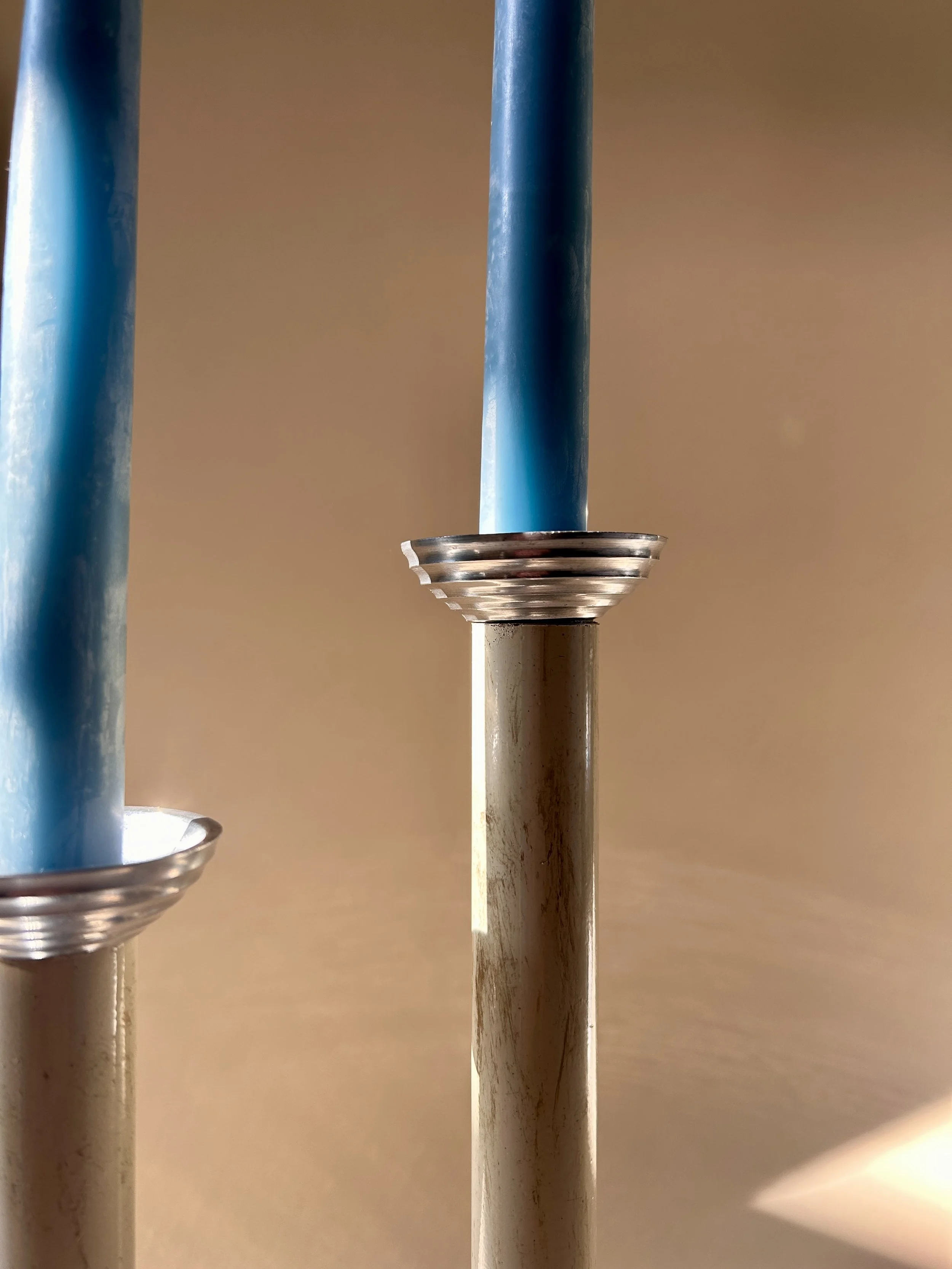Pair of tall vintage taper candlesticks with slender neutral-colored columns and polished silver tone stepped ribbed bases and candle cups.