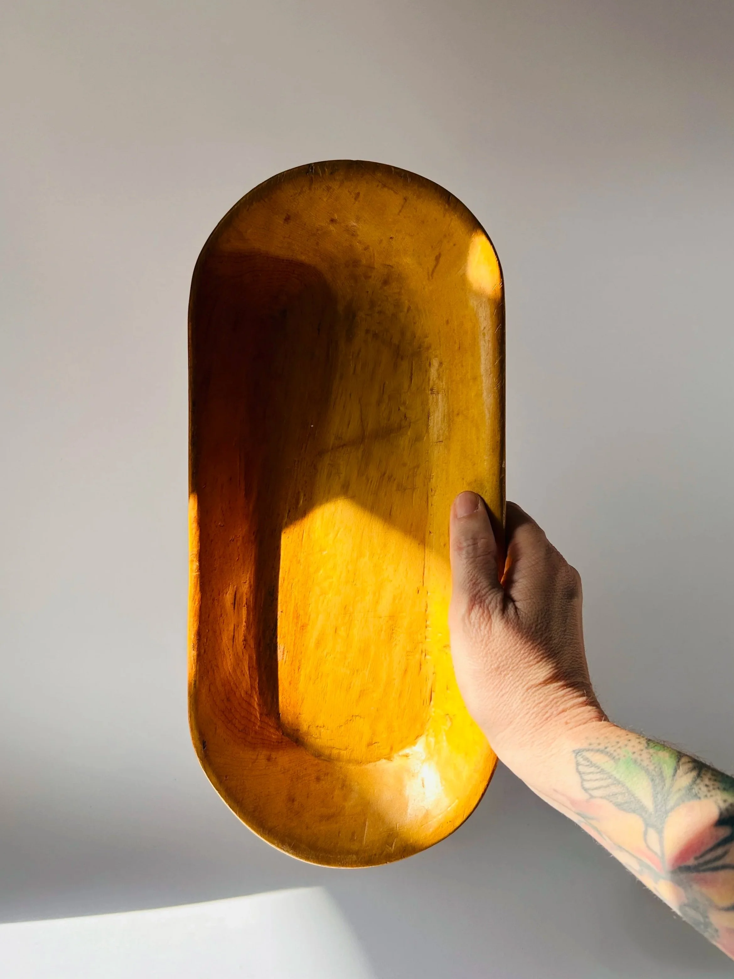 Primitive hand-carved wooden tray with organic shape and warm patina, rustic serving board