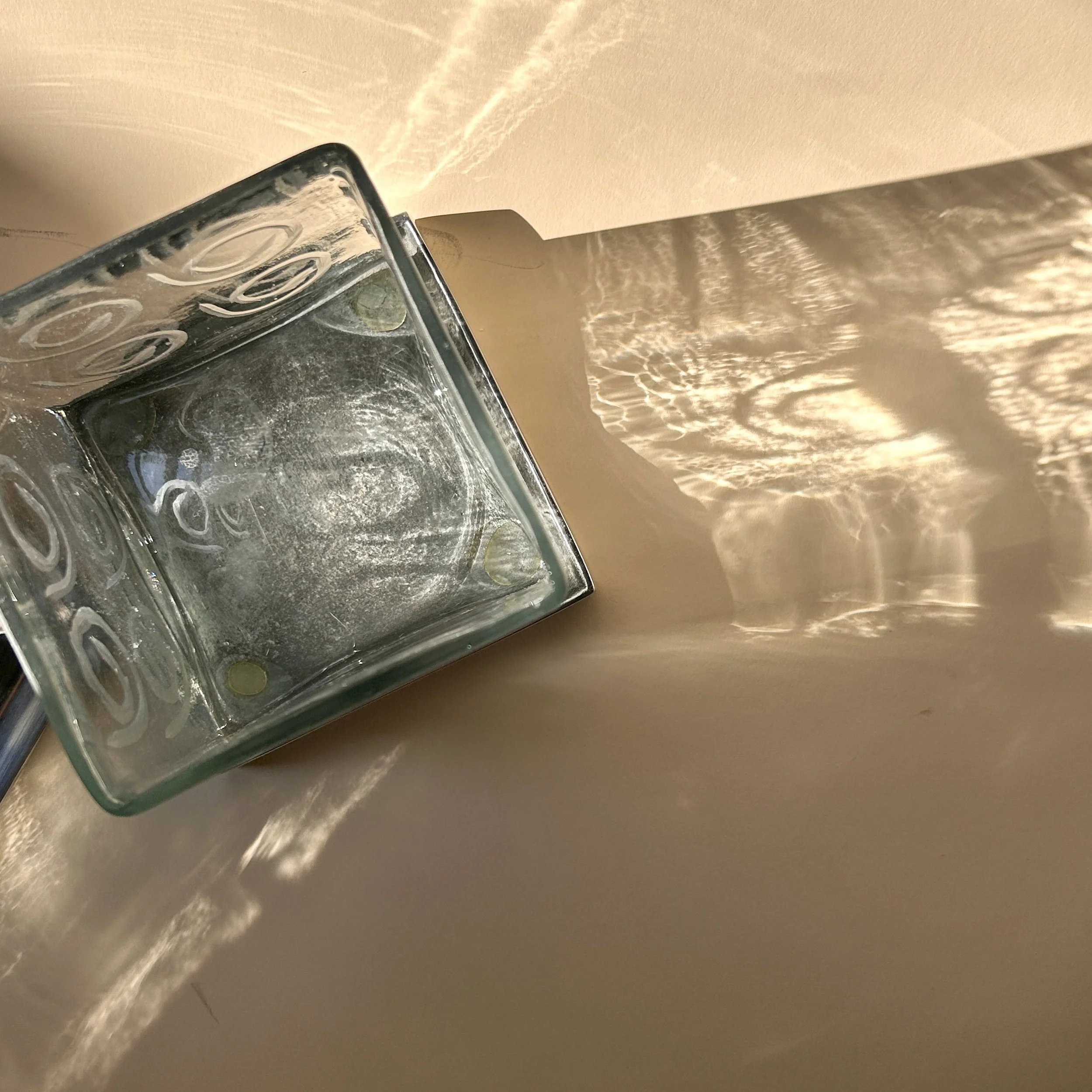 Contemporary square clear glass canisters with etched spiral patterns, silver-tone metal bases, and peaked metal lids in two different heights.