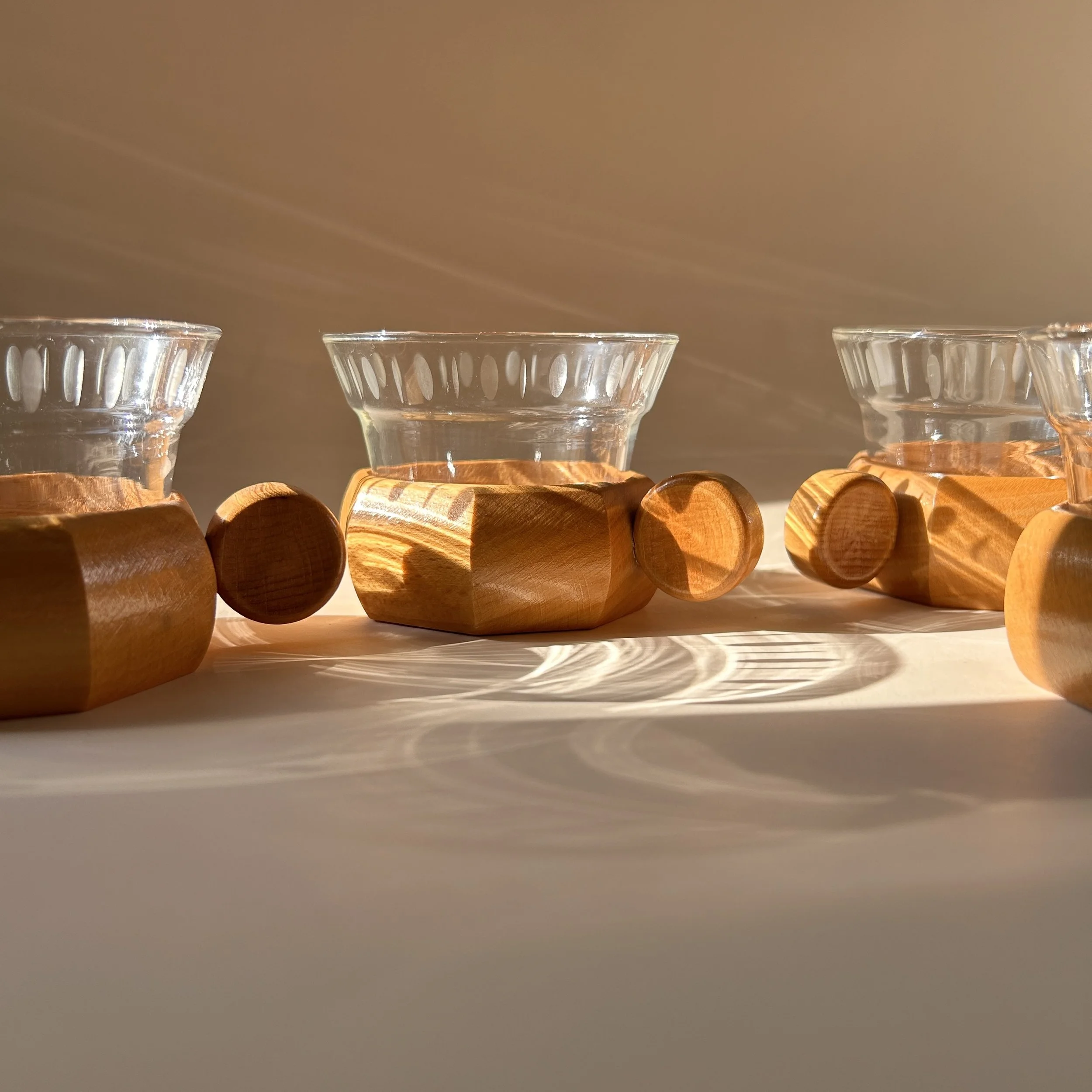 Set of four vintage German clear glass tea cups with frosted oval decoration, faceted wooden holders and round wood handles.