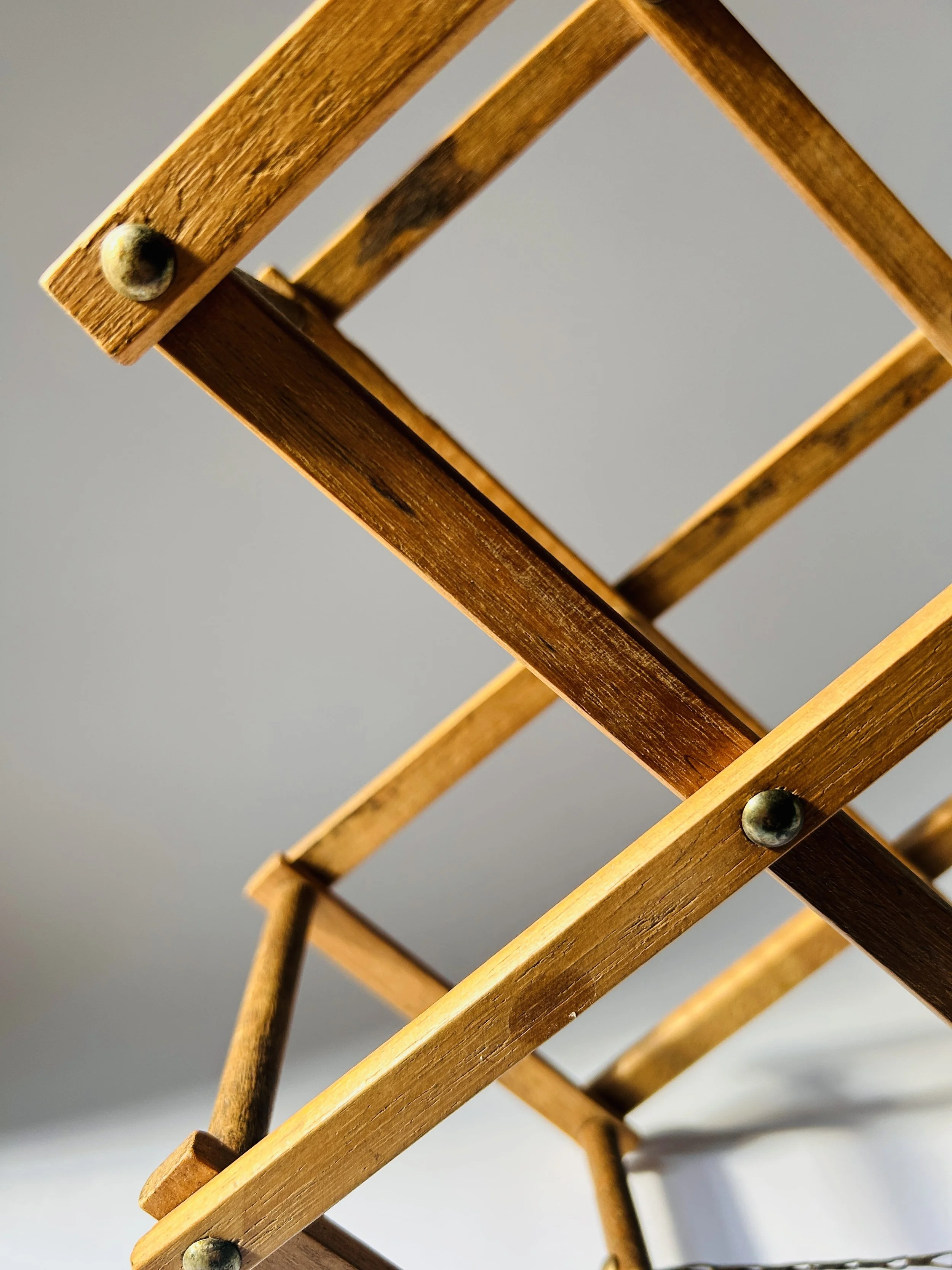 Mid-century expandable wooden wine rack holding five bottles, folding geometric bar storage