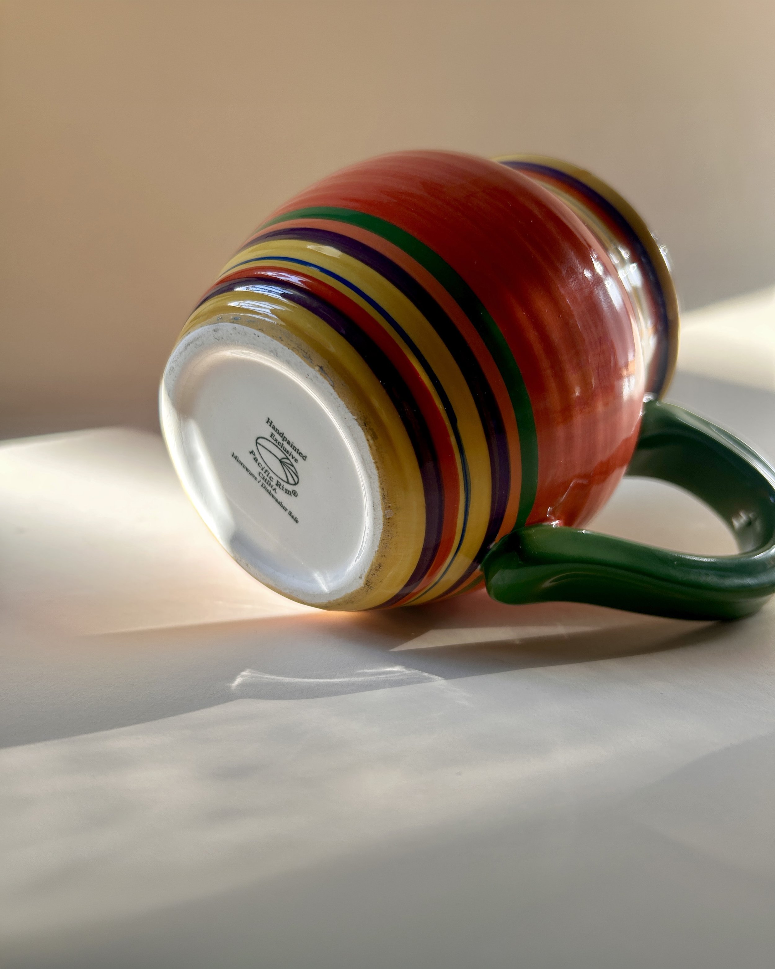 Set of three colorful Pacific Rim Santa Fe stoneware mugs with hand-painted multicolor stripes and contrasting handles and interiors.