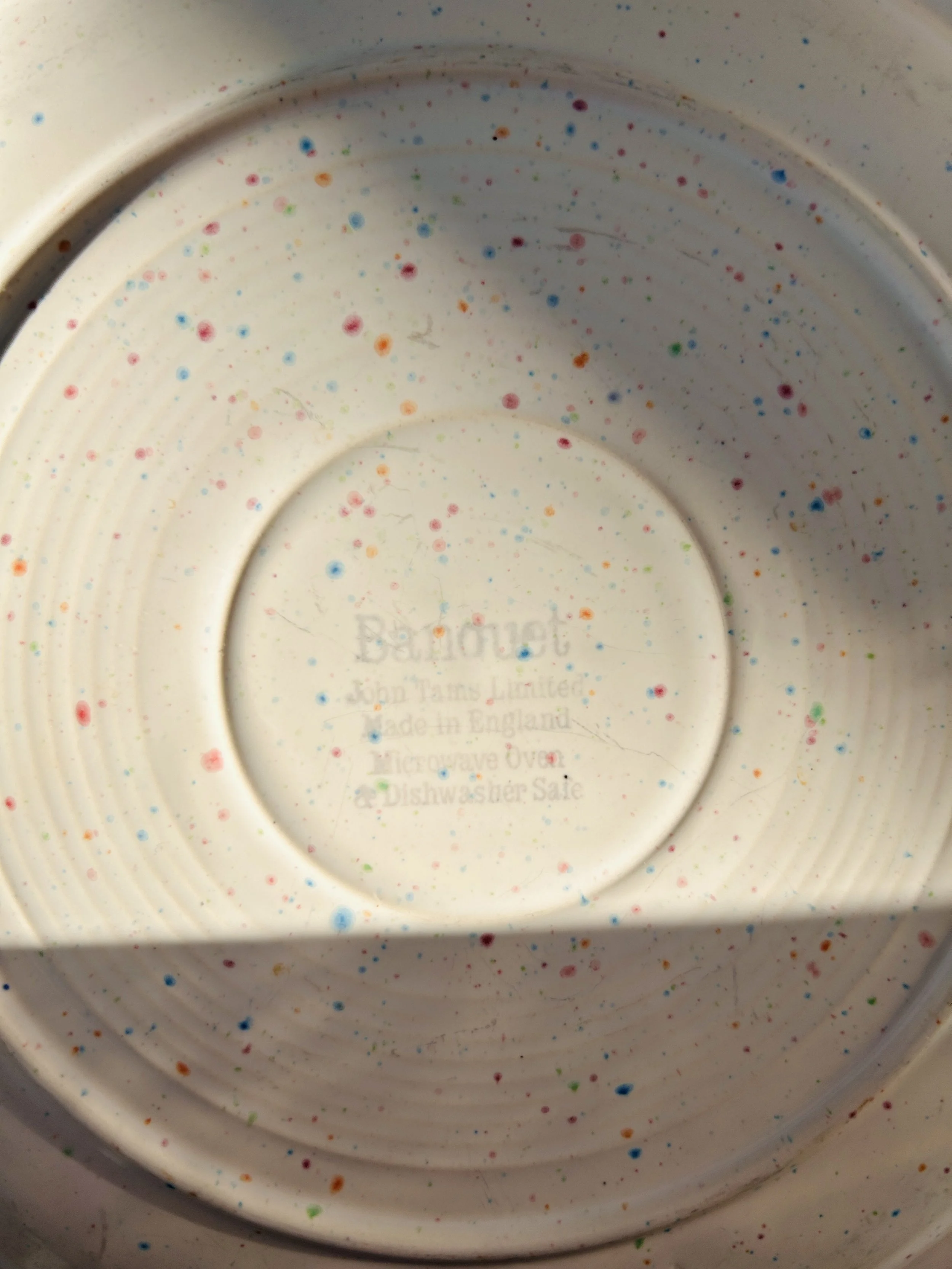 set of three cream stoneware plates with colorful confetti speckle pattern