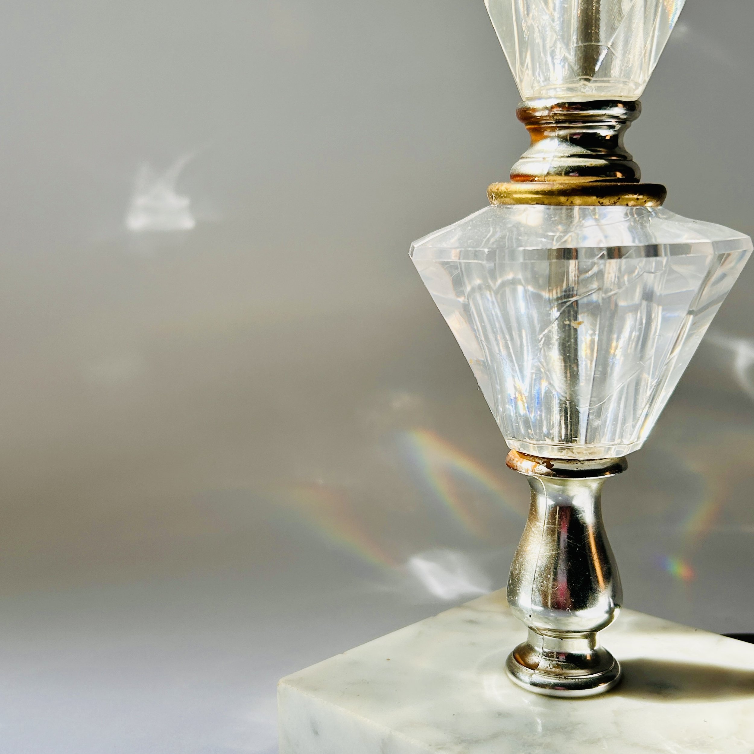 Vintage table lamp with faceted clear crystal-look elements, silver-tone metal accents, pale marble square base, and exposed red bulb.