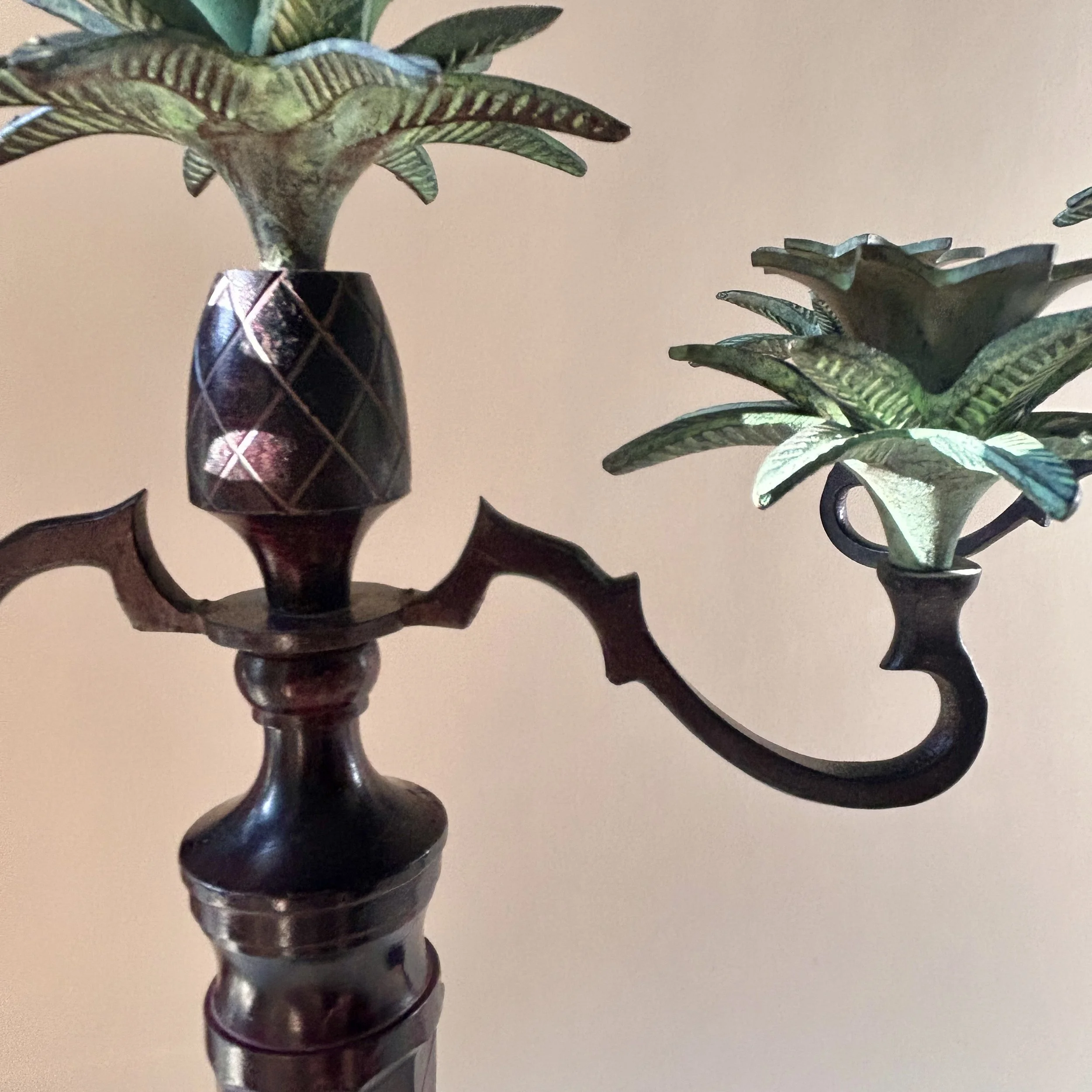 Pair of tall vintage three light candelabras with dark ornate bases, sweeping arms and sculptural green patinated palm leaf candle cups.