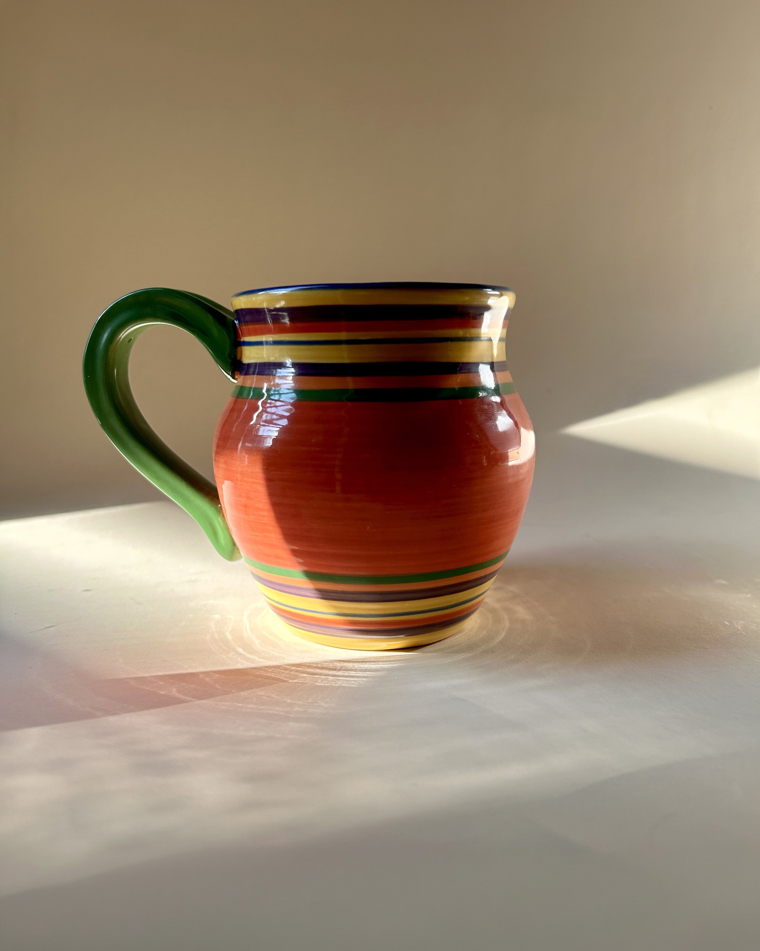 Set of three colorful Pacific Rim Santa Fe stoneware mugs with hand-painted multicolor stripes and contrasting handles and interiors.