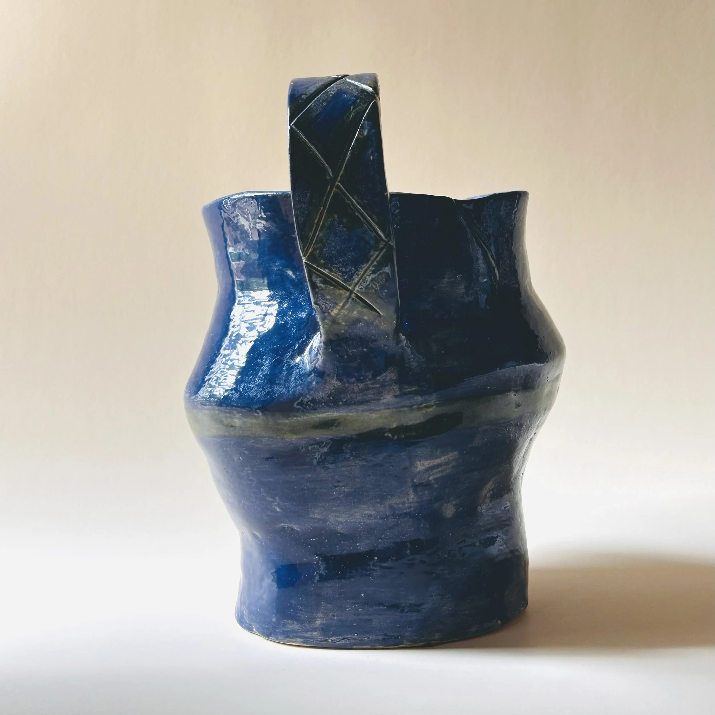 hand built dark blue studio pottery pitcher with sculptural handle