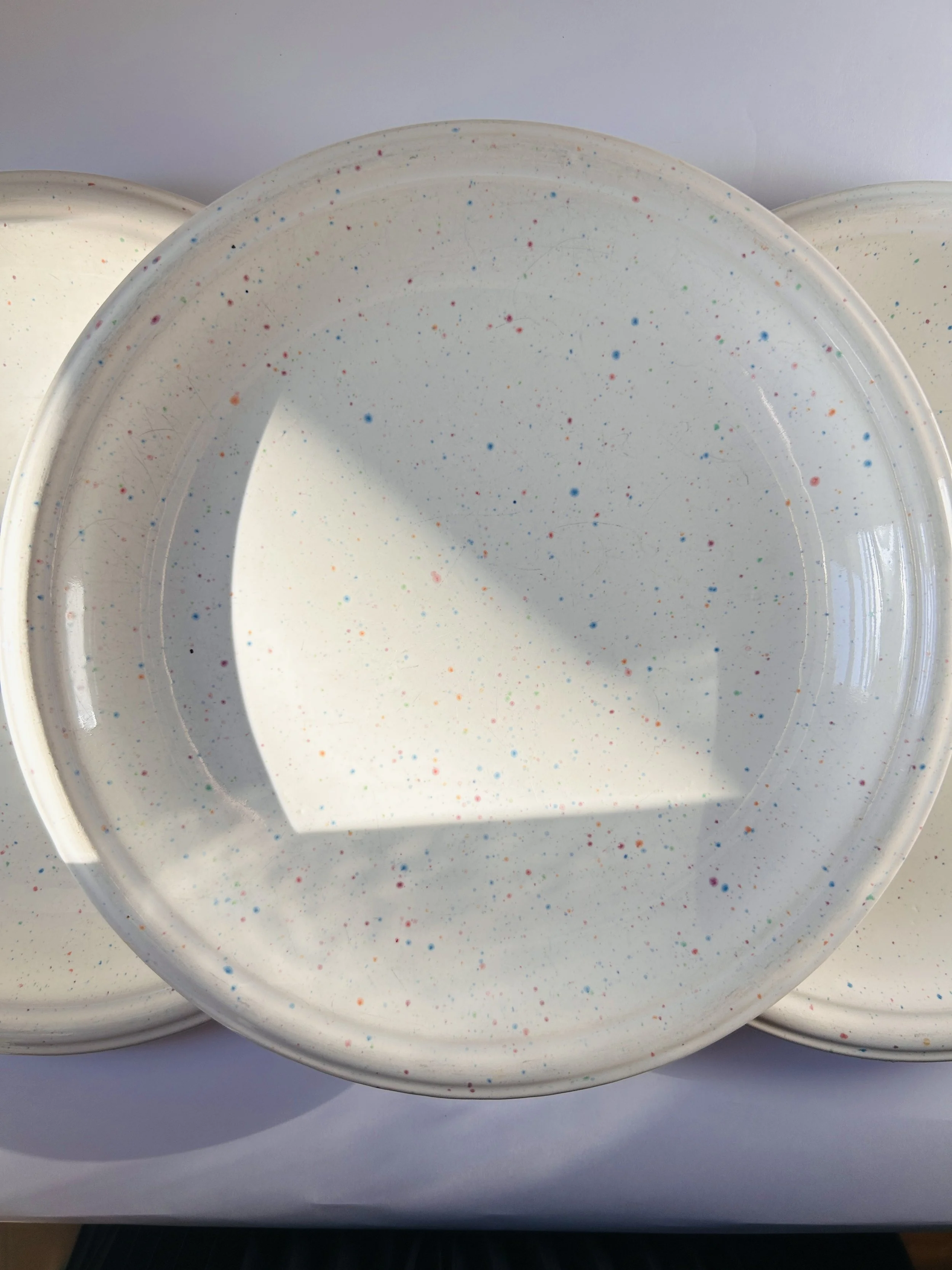 set of three cream stoneware plates with colorful confetti speckle pattern
